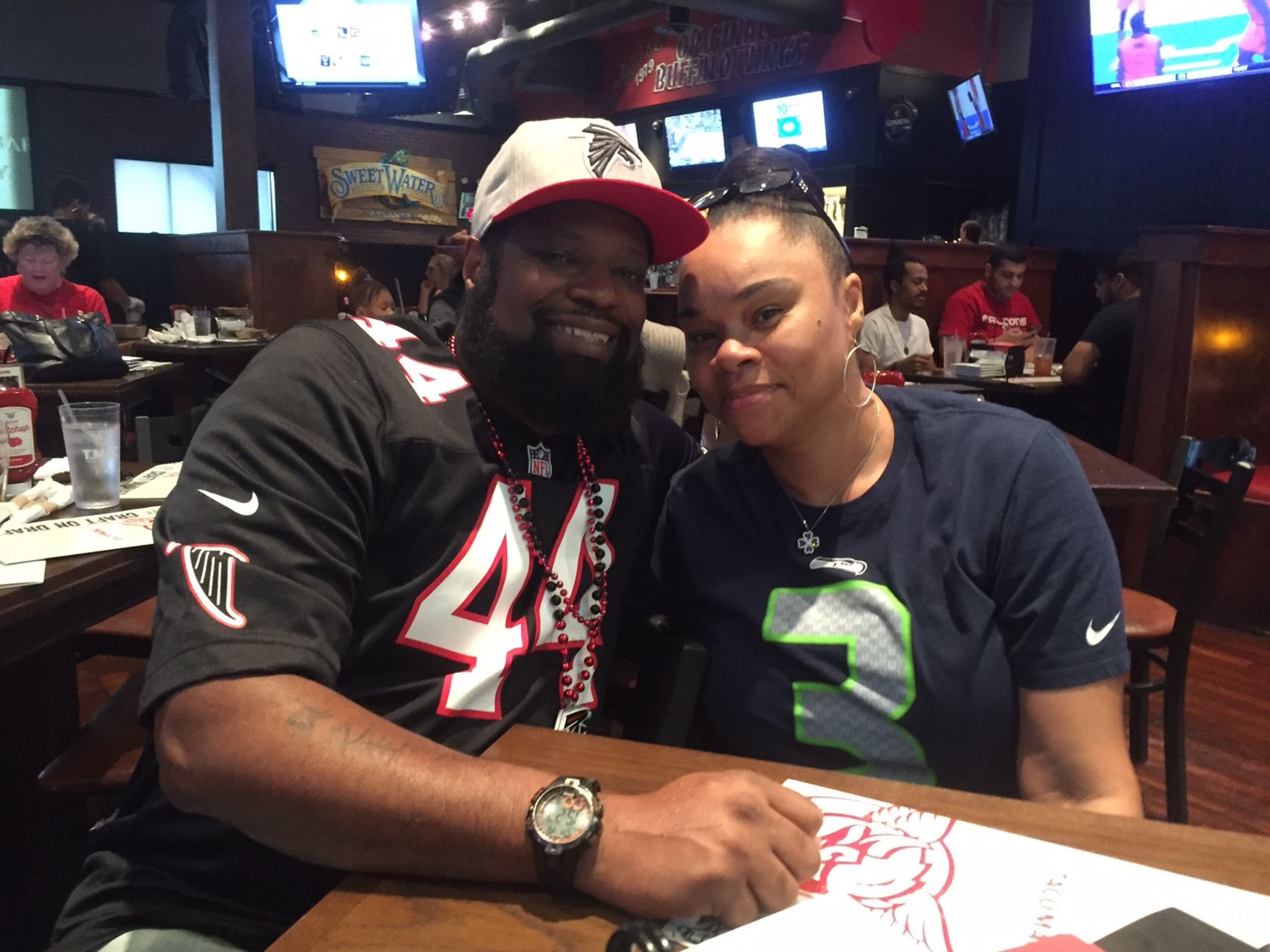 Henry and Tammie Carter momentarily put their football differences aside to pose for a picture before the Falcons-Seahawaks game. ERIC STIRGUS/STAFF