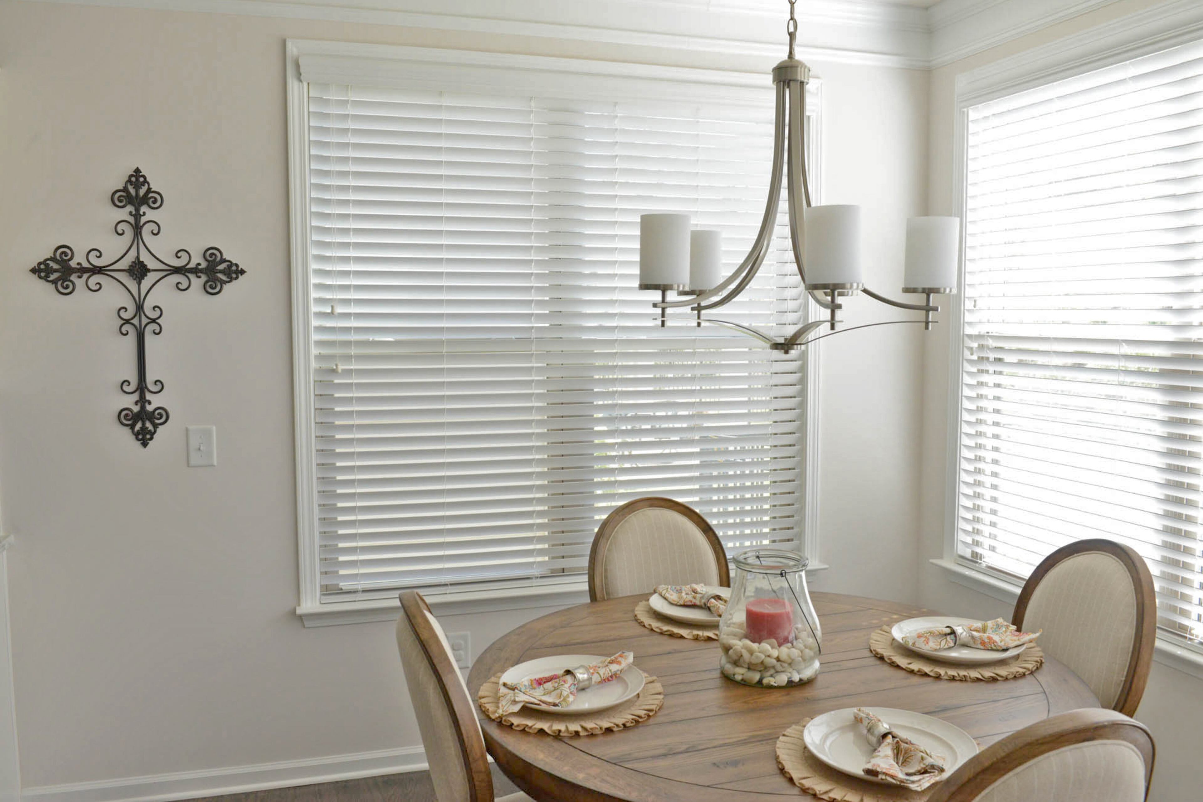 A round kitchen table from Havertys goes with the dining room table, adding warm farmhouse tones to the classic space, and a five-light Savoy House chandelier echoes the style of dining room fixture.