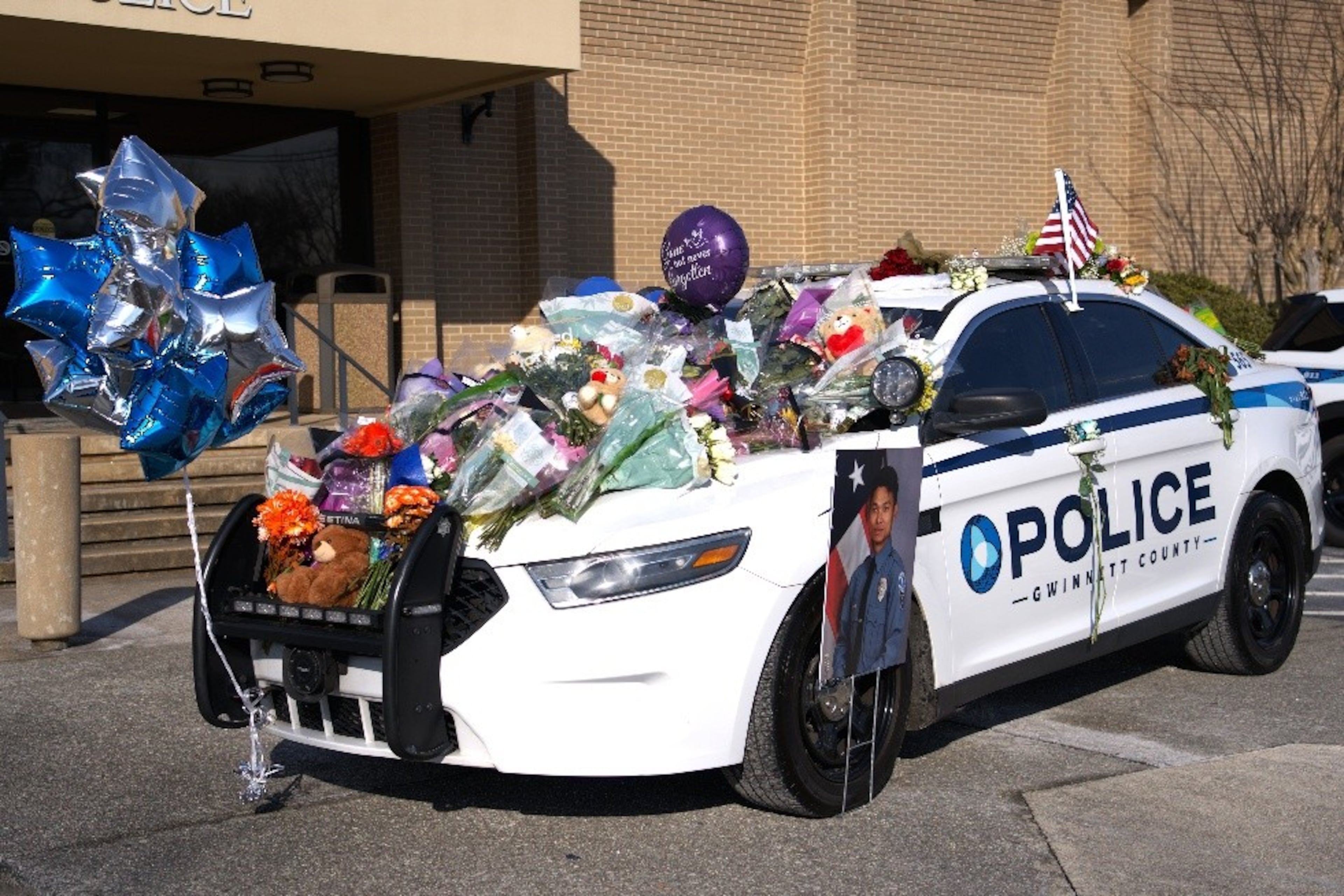 Floral bouquets, balloons and other items cover the patrol vehicle of Gwinnett County police officer Pradeep Tamang as part of a memorial to him, outside police headquarters. (Courtesy of Gwinnett County Police Department)