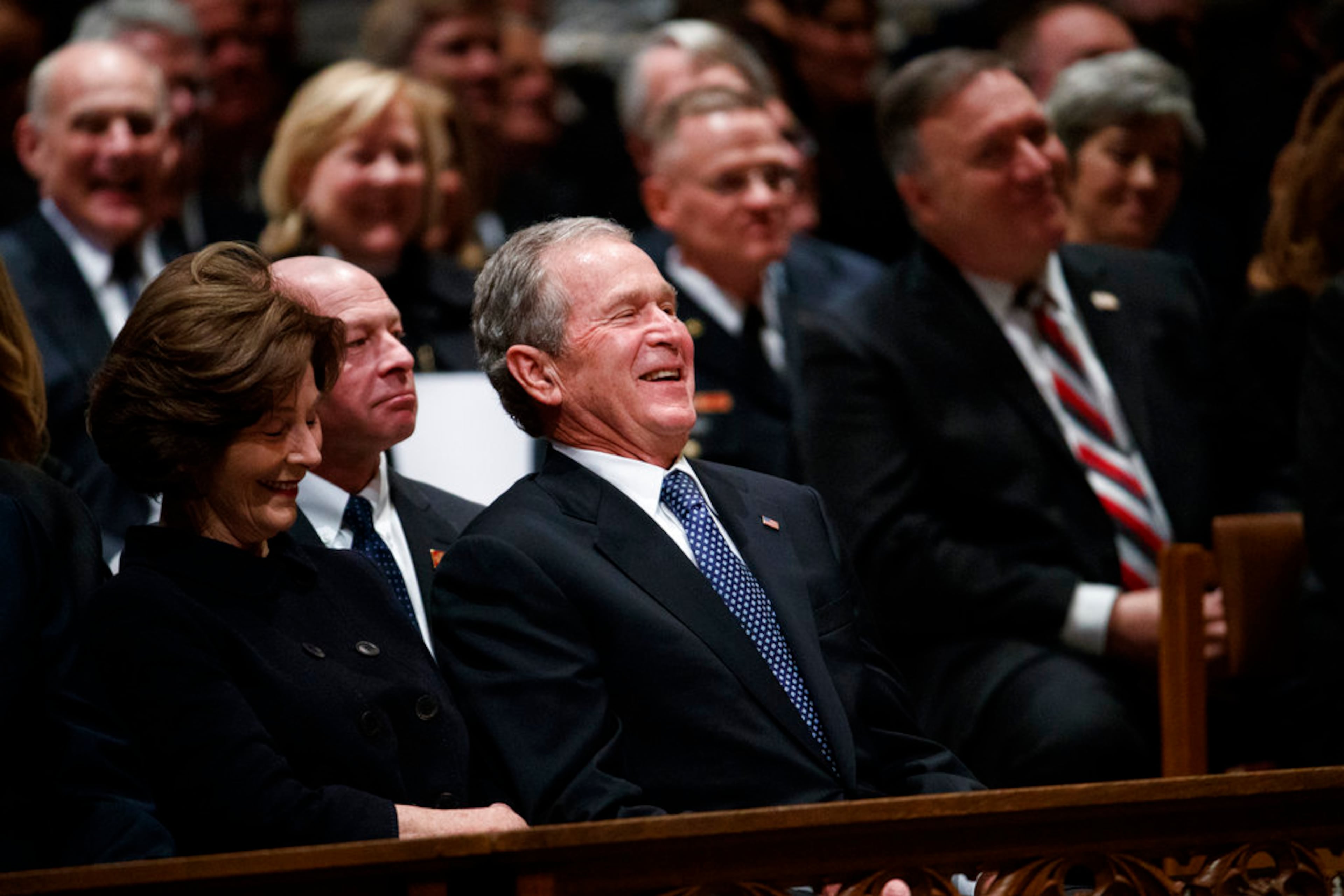 Former President George W. Bush and Laura Bush share a laugh as a story is told about his father, former President George H.W. Bush, during a State Funeral at the National Cathedral, Wednesday, Dec. 5, 2018, in Washington. (AP Photo/Evan Vucci)