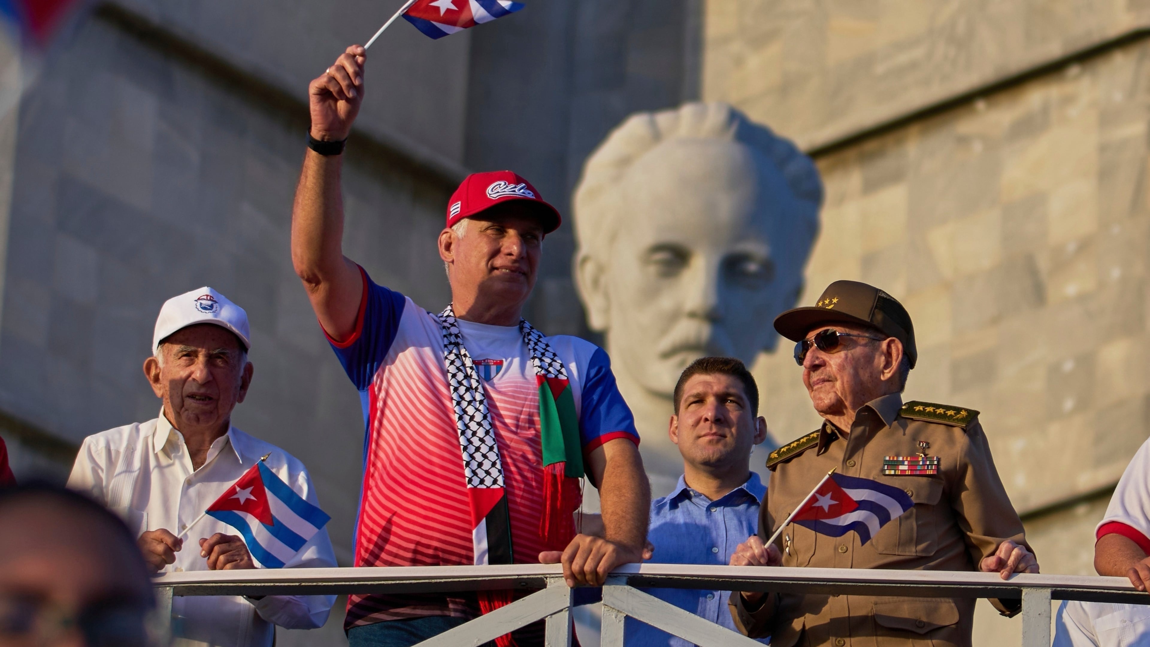 FILE - Cuba's President Miguel Diaz-Canel holds up a Cuban flag as he watches the May Day parade next to Raul Castro, second from right, and Raul Castro's grandson, Raul Guillermo Rodriguez Castro, at Revolution Square in Havana, May 1, 2025. (AP Photo/Ramon Espinosa, File)