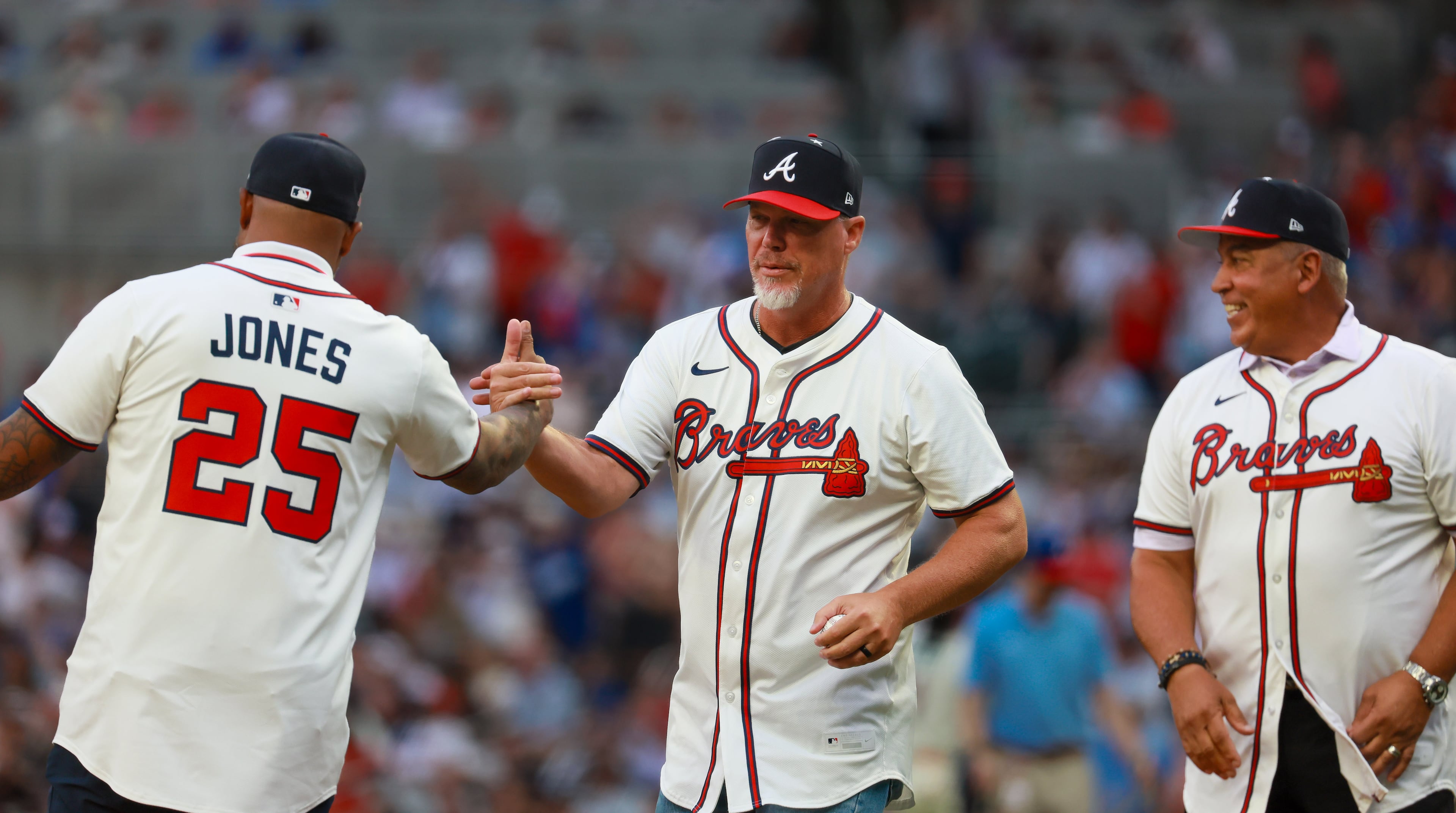 Atlanta Braves baseball greats Chipper Jones (center) and Andruw Jones (left) greet each other as Andrés Galarraga watches during opening ceremonies for the MLB All-Star Game at Truist Park in Atlanta on Tuesday, July 15, 2025. (Jason Getz/AJC)