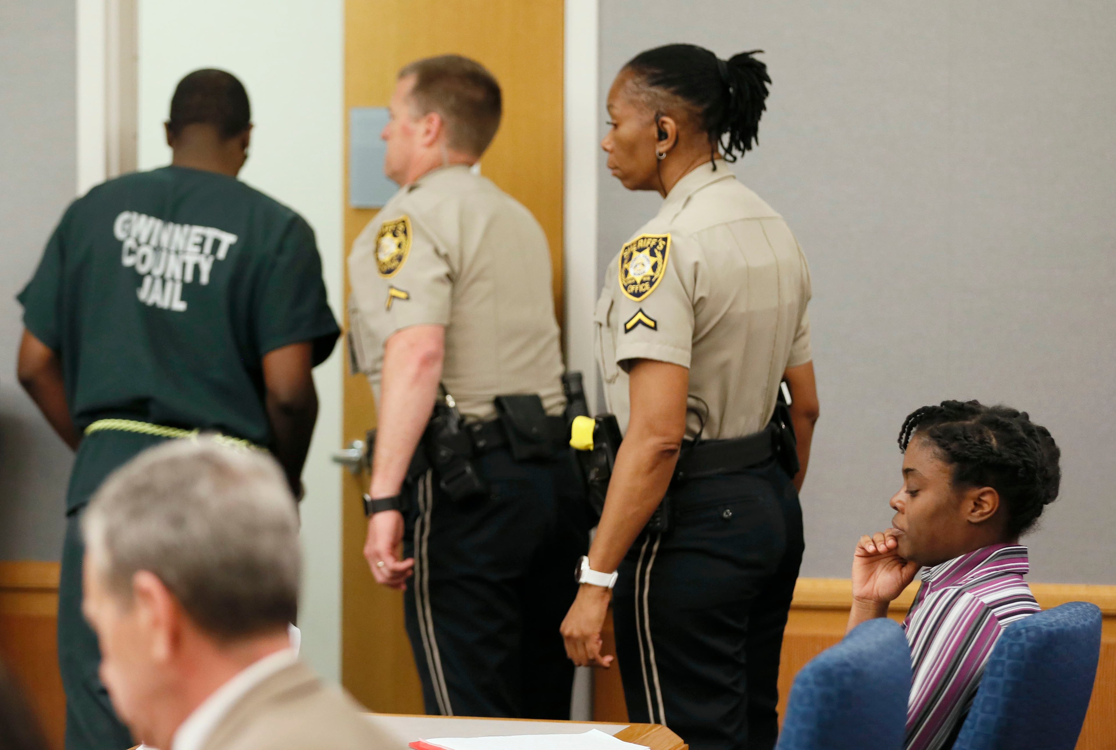 April 25, 2019 - Lawrenceville - Emani Moss' father, Eman Moss, is escorted from court after he testified at his wife's capital murder trial. Tiffany Moss (right) showed little emotion during his testimony. Eman Moss agreed to a plea deal that allowed him t avoid the penalty in exchange for testifying against Tiffany Moss. The prosecution continued for the second day in the Tiffany Moss death penalty trial with the testimony of Eman Moss. Moss, who is representing herself, again declined to ask questions of the prosecution witnesses. Bob Andres / bandres@ajc.com