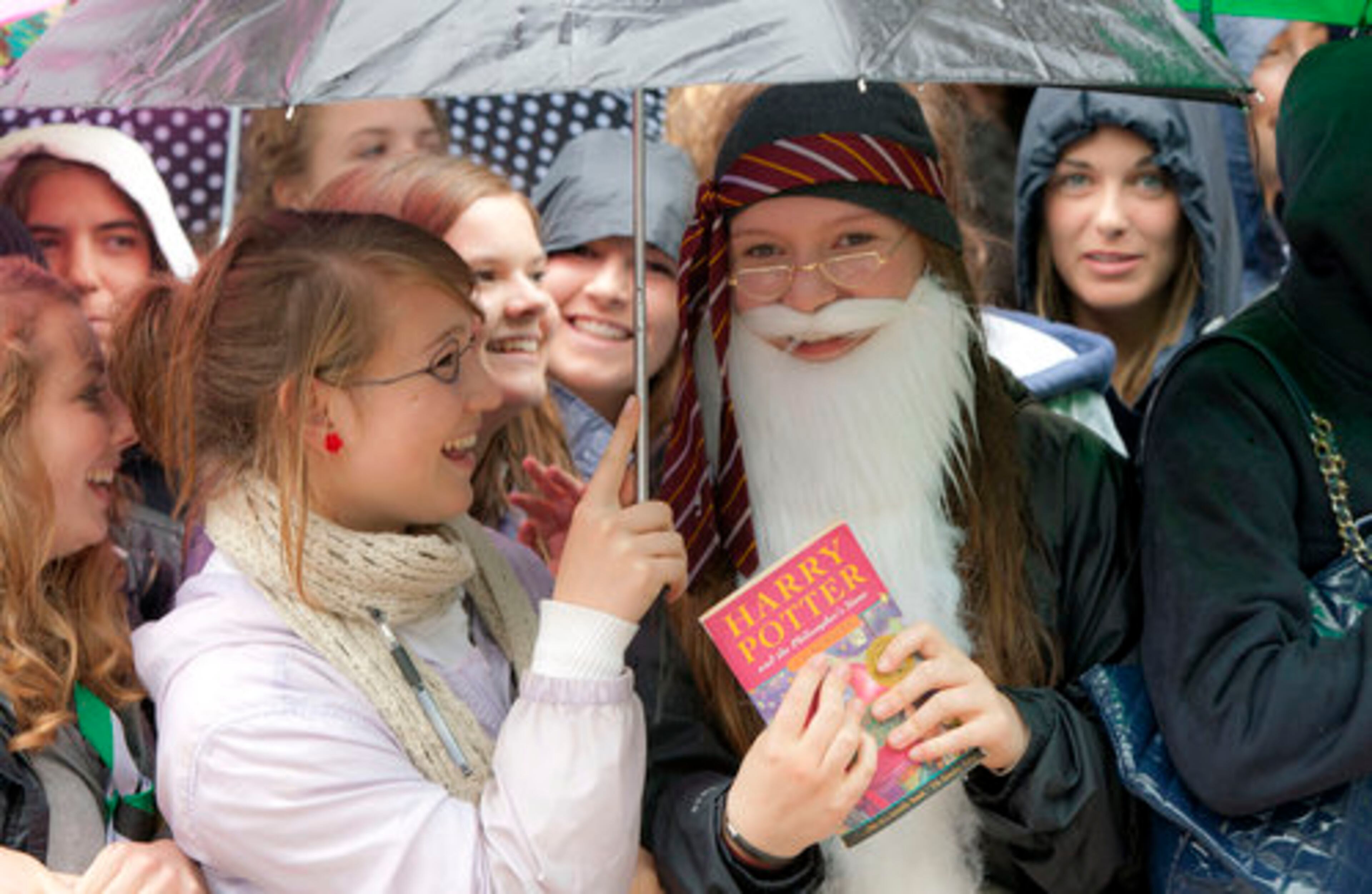 Harry Potter fan Ellie Coote, 15, from Oxford, dressed as Professor Dumbledore, clutches a book in the rain outside the cinema in Leicester Square, central London, for the world premiere.