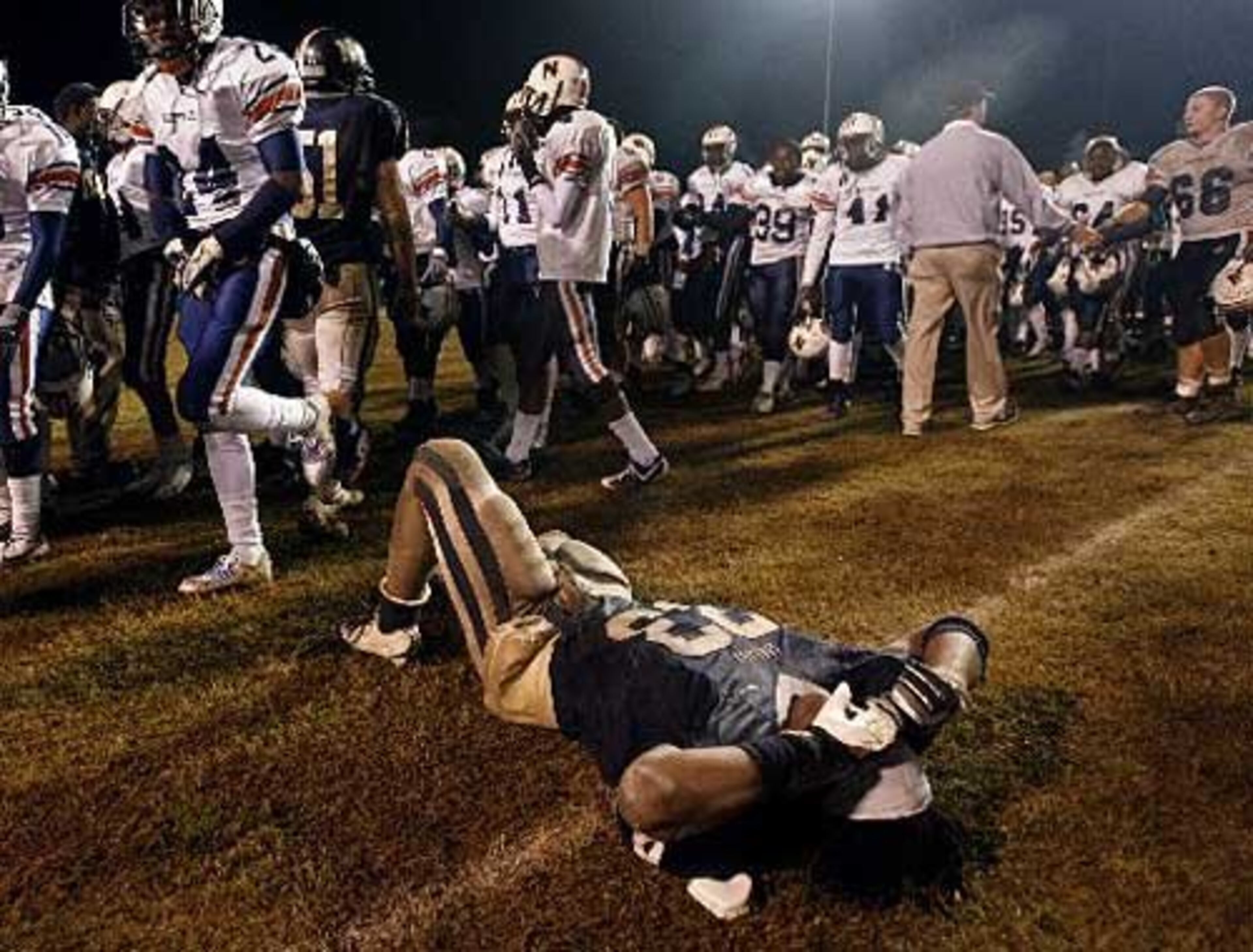Newnan linebacker Alexander Ogletree (33) hits the ground and reacts to their 29-24 loss to Northside-Warner Robins during the post-game handshake.