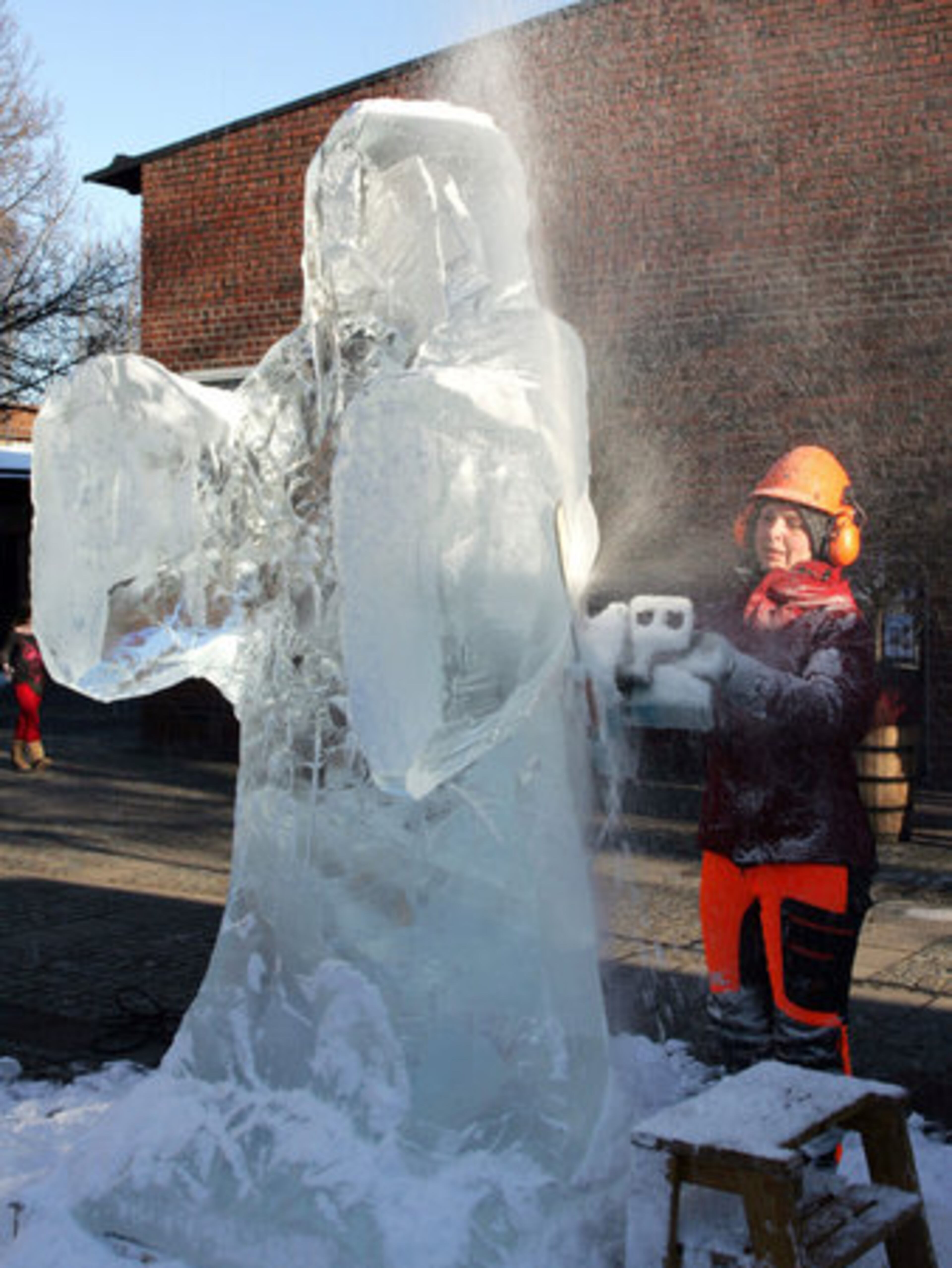 Wearing heavy-duty gear, artist Tjaasa Gusfors uses a chainsaw as she shaves the ice block to create a statue of Jesus.