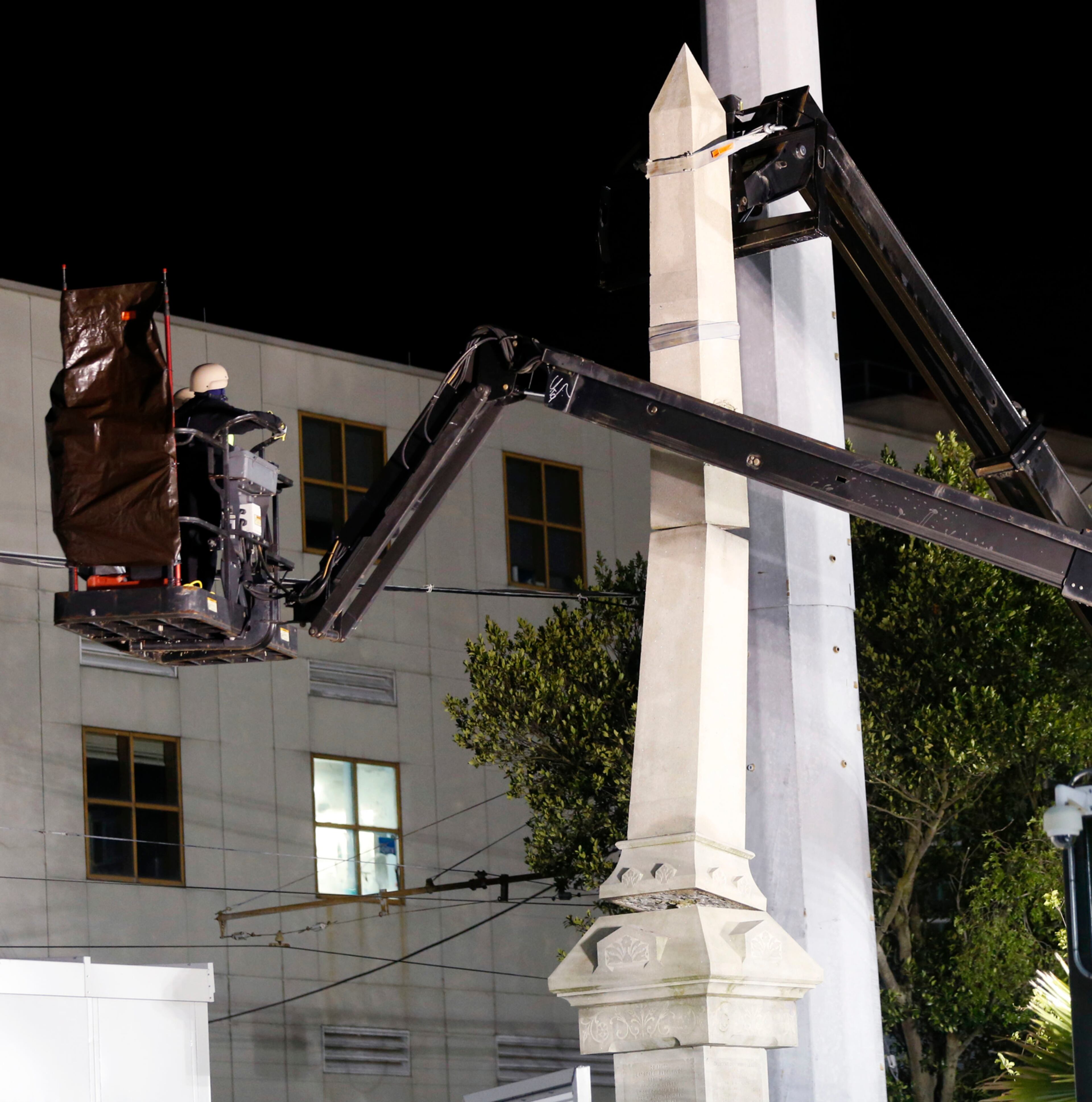 Workers dismantle the Liberty Place monument Monday, April 24, 2017, which commemorates whites who tried to topple a biracial post-Civil War government, in New Orleans. It was removed overnight in an attempt to avoid disruption from supporters who want the monuments to stay. (AP Photo/Gerald Herbert)