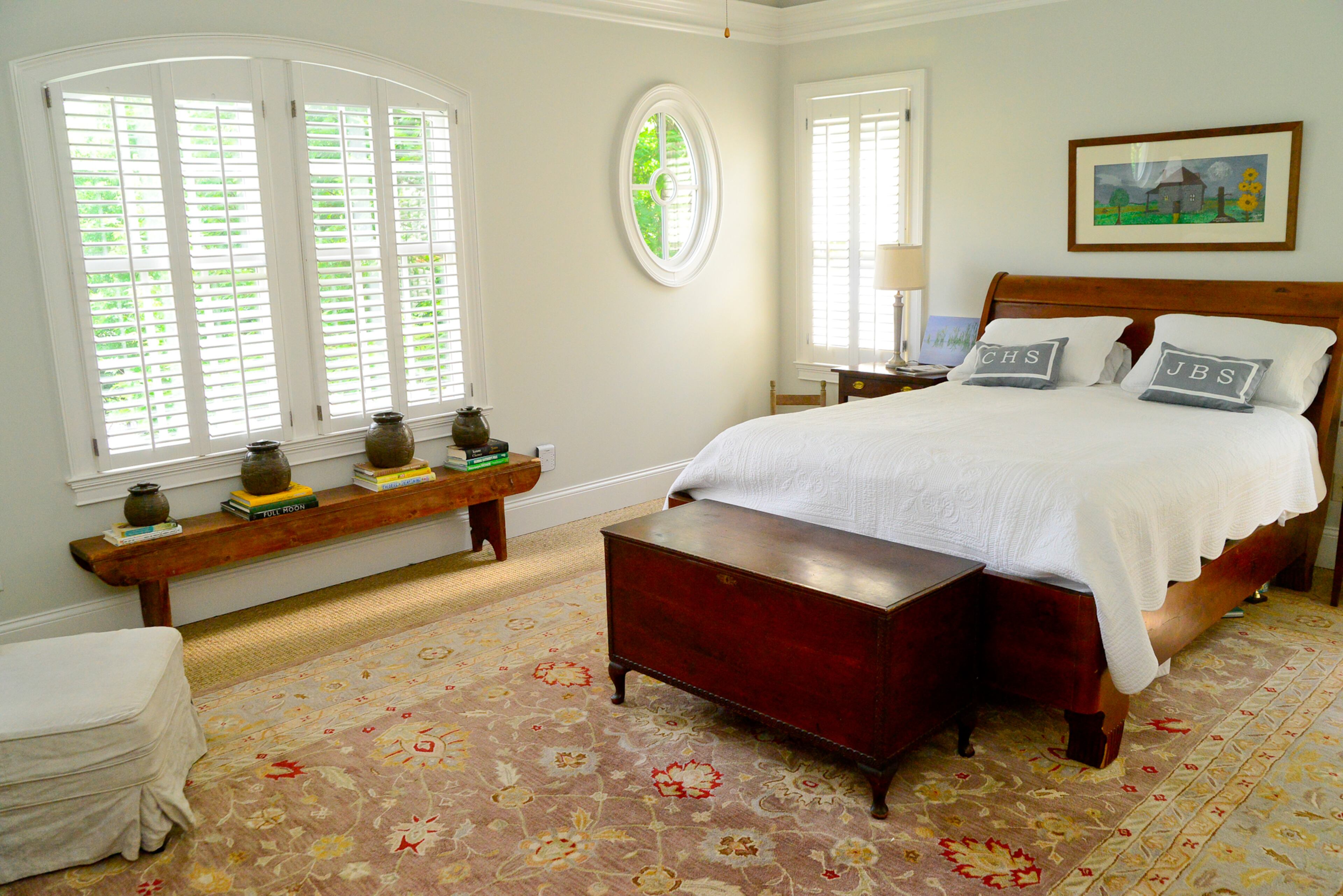 Arched and oval windows are key architectural elements in the master bedroom, which has a vaulted ceiling and furnishings that fit with the couple's love of antiques and folk art.