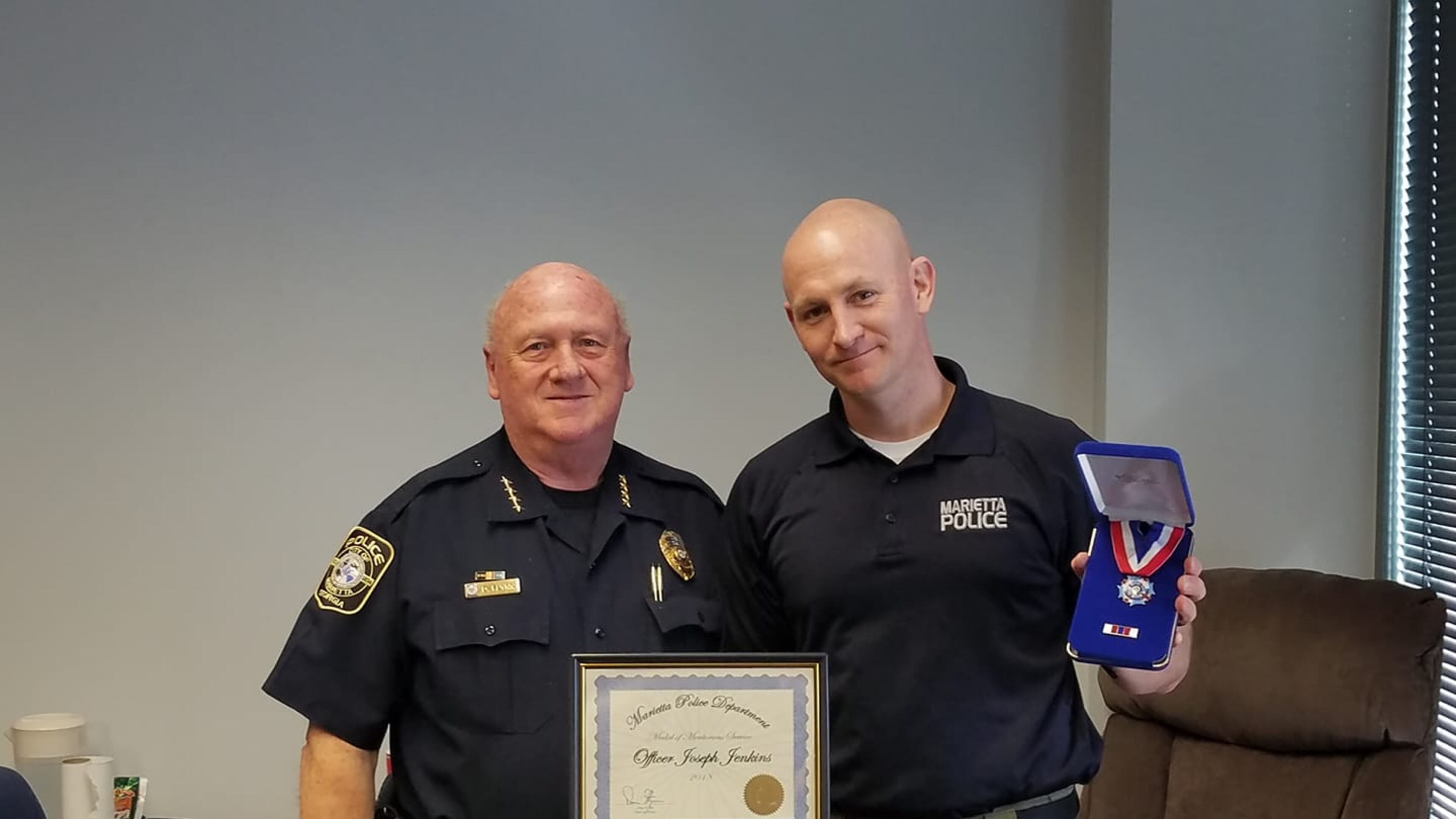 Marietta police chief Dan Flynn, left, recognized office Joe Jenkins for saving the life of a man who had been shot and left for dead.