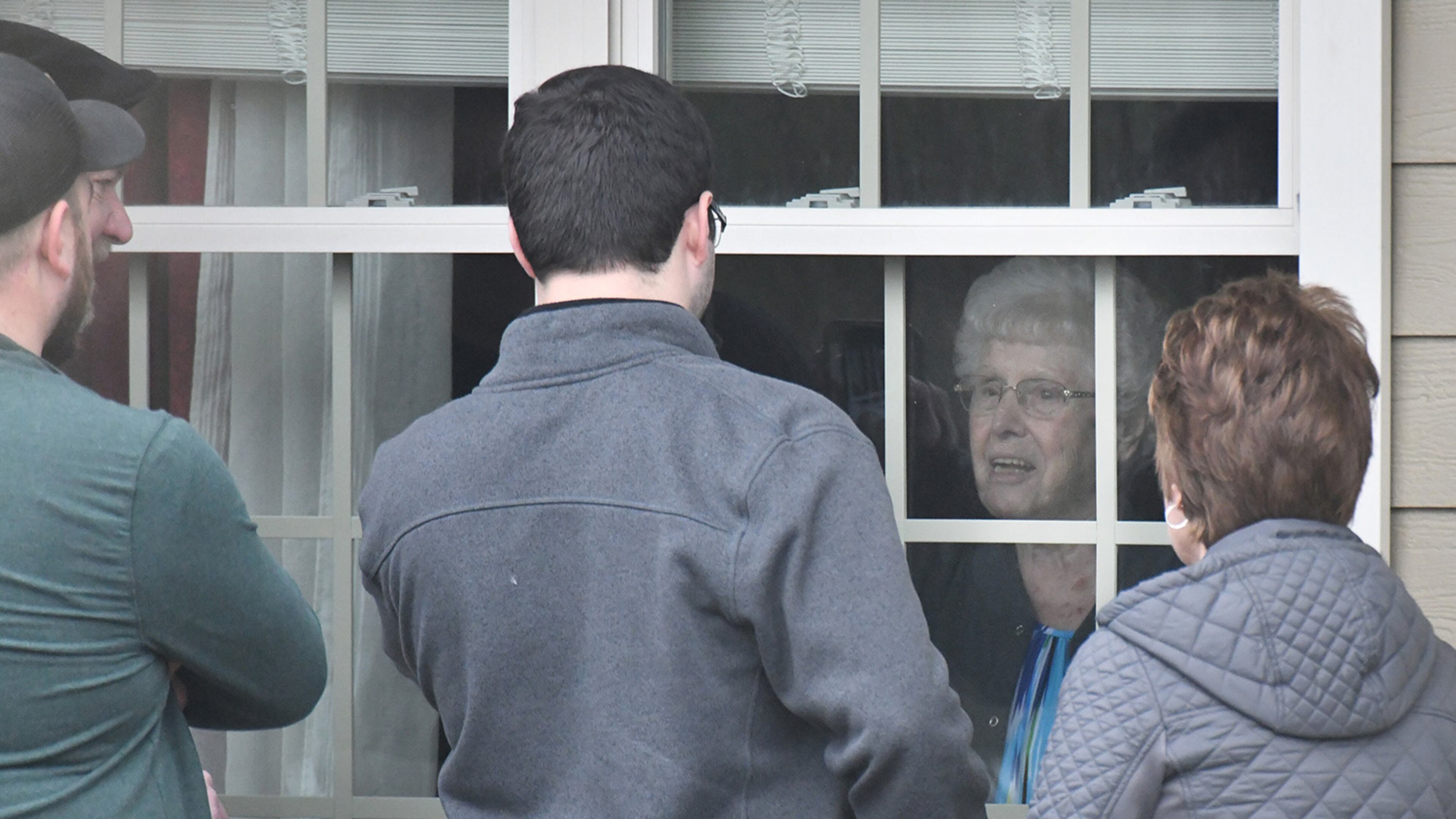 Family members visit a relative through the window at The Retreat at Canton after delivering a birthday balloon and a gift bag. Three residents and an employee of the home have “tested presumptively positive” for COVID-19. Residents are self-isolating in their rooms, and the home is not admitting visitors. (Hyosub Shin / Hyosub.Shin@ajc.com)