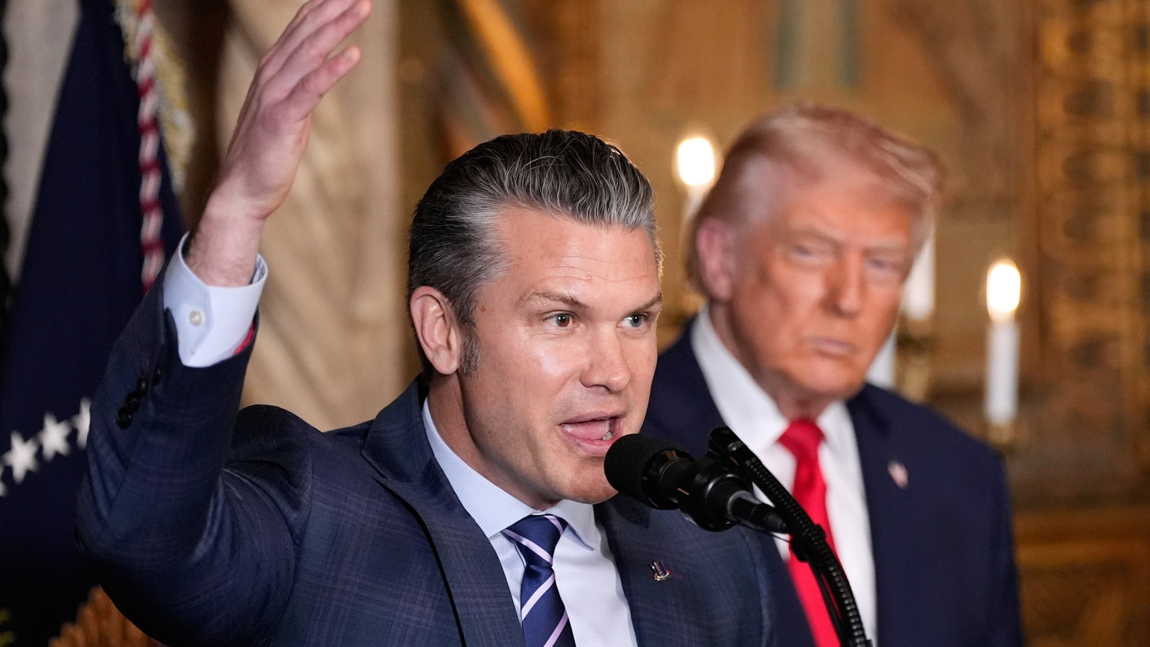 Defense Secretary Pete Hegseth speaks as President Donald Trump looks on, at Trump's Mar-a-Lago club, Monday, Dec. 22, 2025, in Palm Beach, Fla. (AP Photo/Alex Brandon)