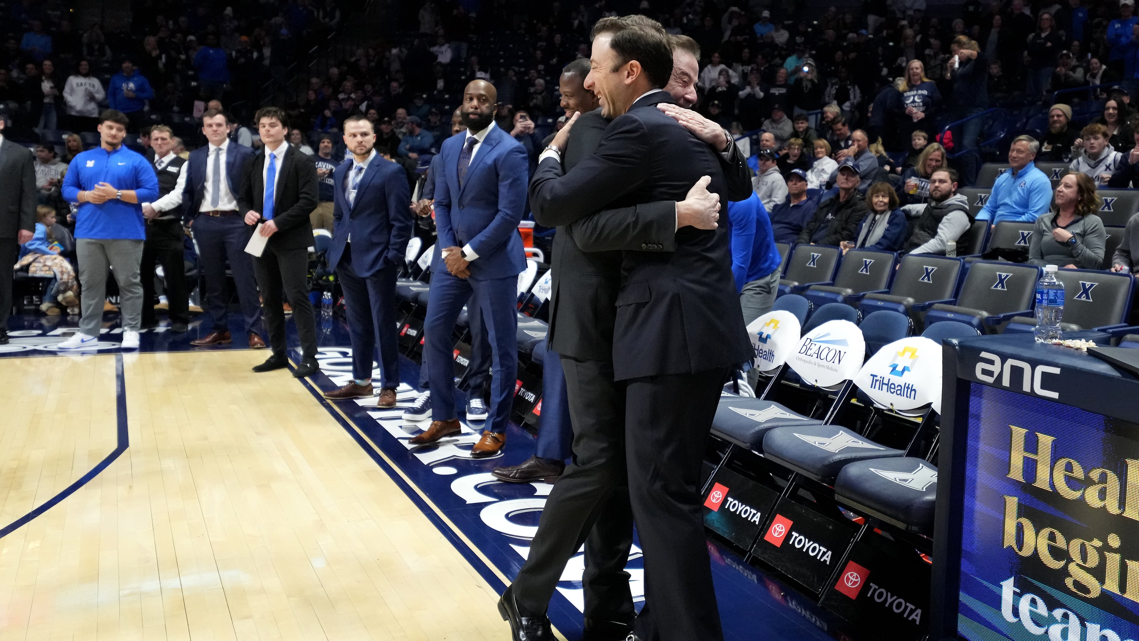 Xavier head coach Richard Pitino, right. wearing a full suit like his father, Rick Pitino, left, embraces him before a college basketball game St. John's, Saturday, Jan. 24, 2026, in Cincinnati. (AP Photo/Kareem Elgazzar)