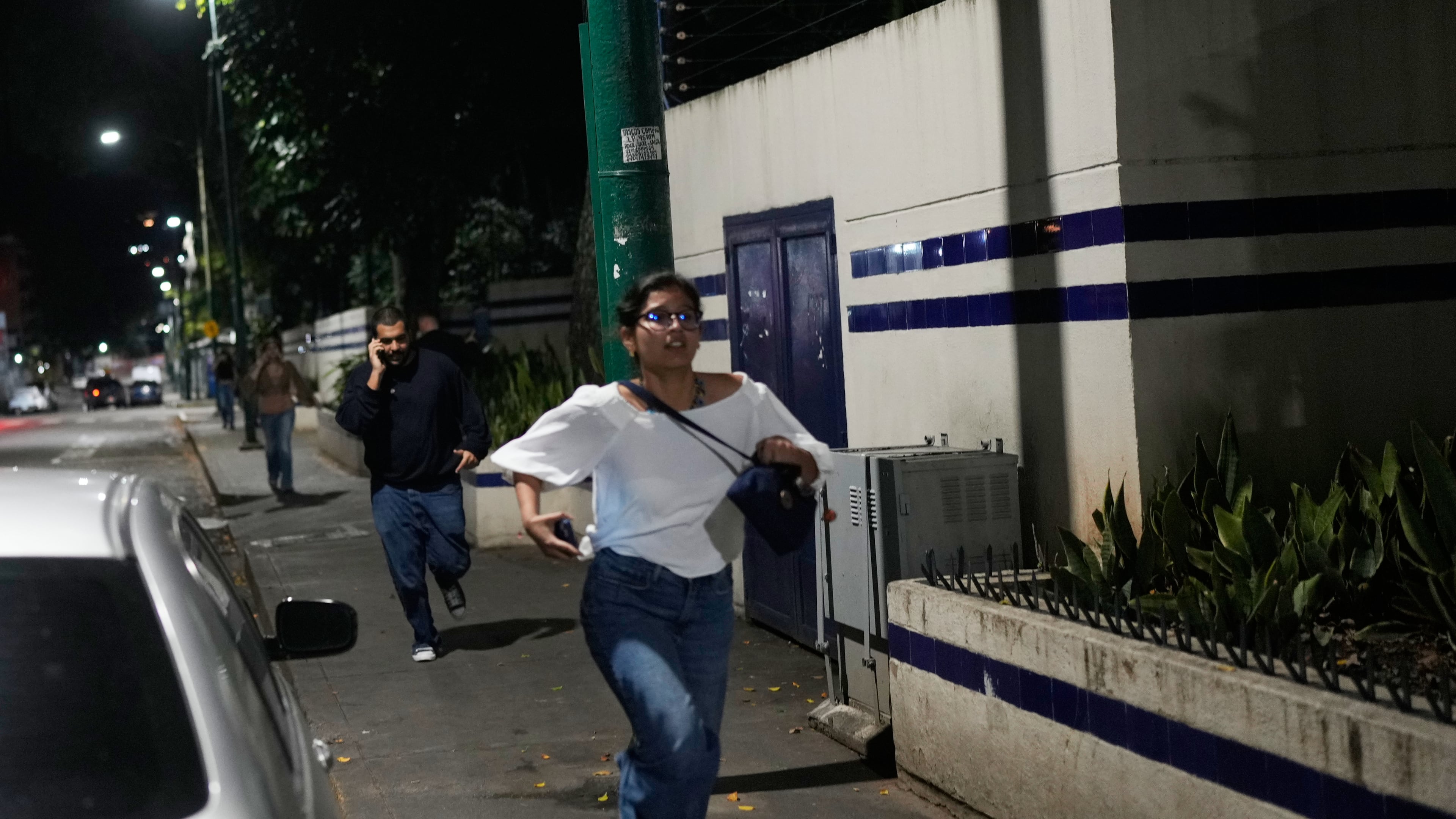 Pedestrians run after explosions and low-flying aircraft were heard in Caracas, Venezuela, Saturday, Jan. 3, 2026. (AP Photo/Matias Delacroix)