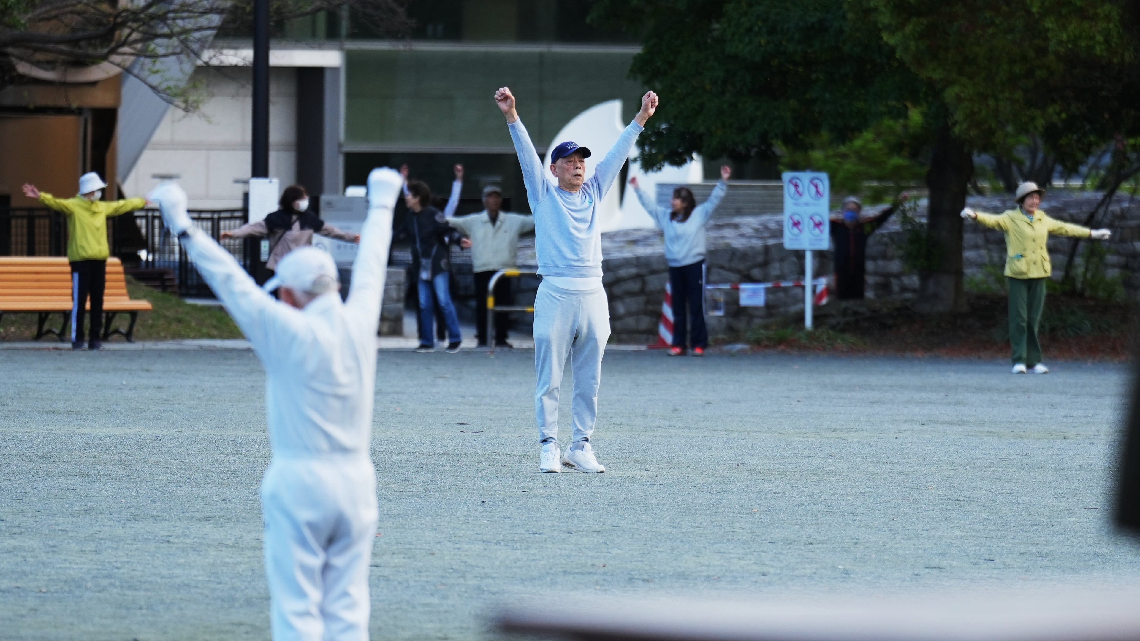 People perform a stretching exercise while listening to music and guidance from radio at a public park in Tokyo, Monday, April 6, 2026. (AP Photo/Hiro Komae)