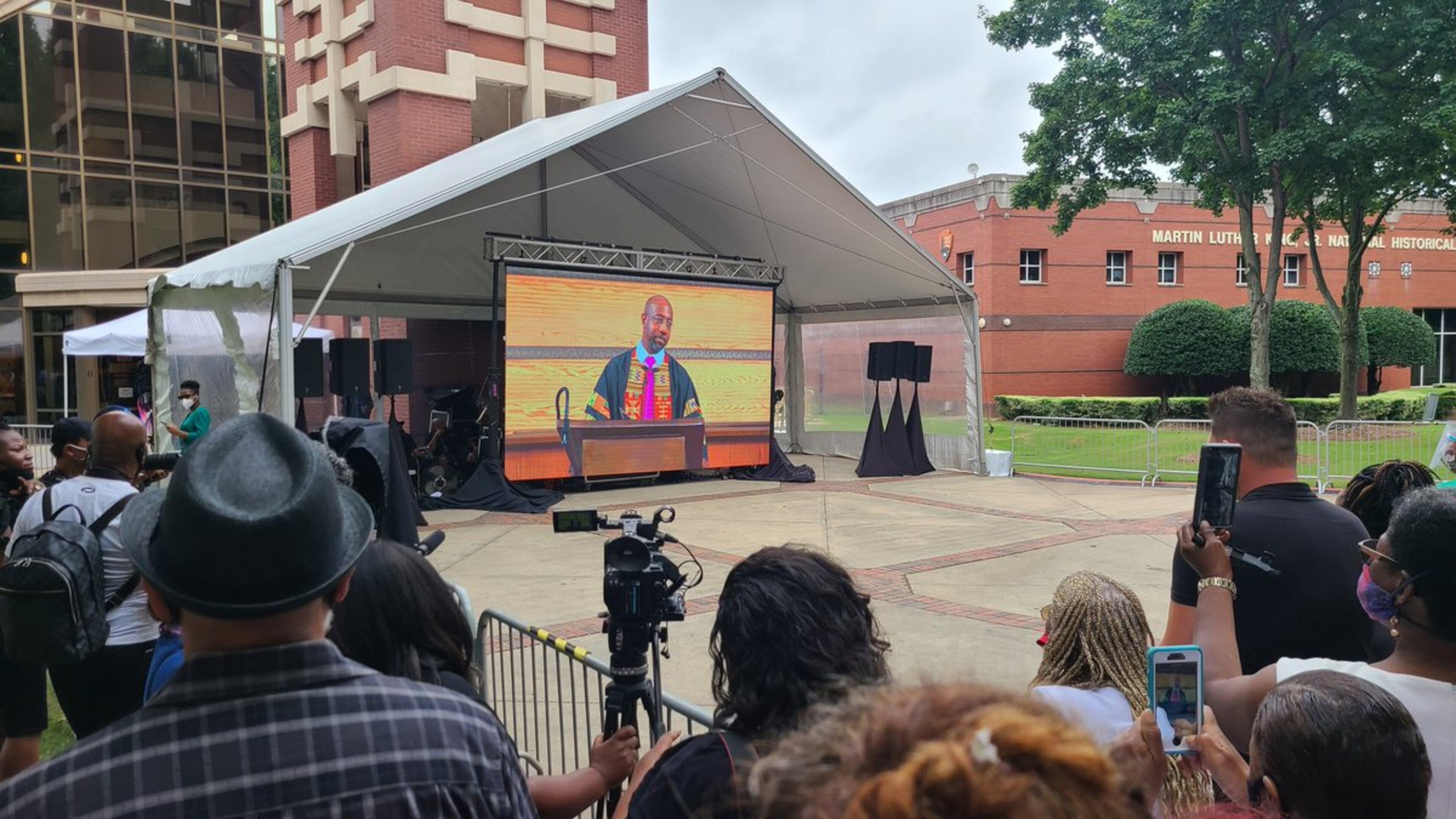 Cheers from the crowd outside Ebenezer Baptist Church watching on a giant TV screen as Nancy Pelosi, Keisha Lance Bottoms, Bill Clinton are seated in the sanctuary at the beginning of the funeral for John Lewis. Rev. Raphael Warnock offers the call to celebration as the family enters. (Maya T. Prabhu / AJC)