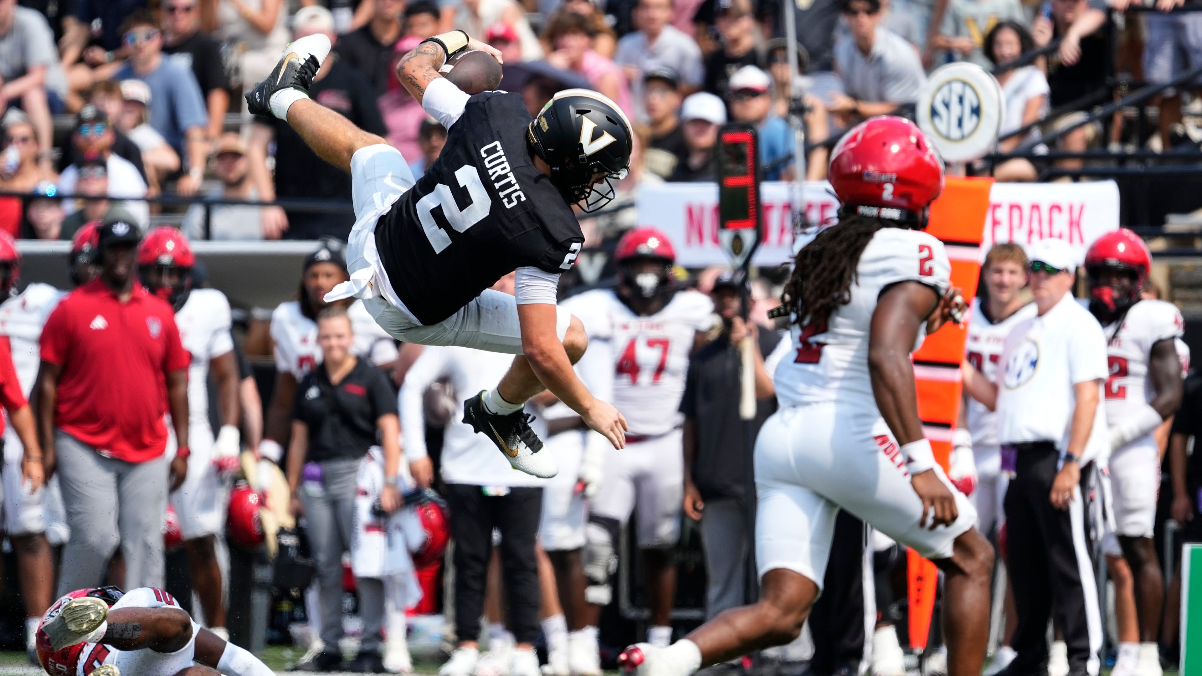 Vanderbilt quarterback Jared Curtis (center) leaps over NC State defensive back Ty White (left) on Saturday, Sept. 19, 2026, in Nashville, Tenn. Curtis’ size and athleticism has certainly impressed Georgia coach Kirby Smart, who was once ready to make him the Bulldogs’ quarterback of the future. (George Walker IV/AP)