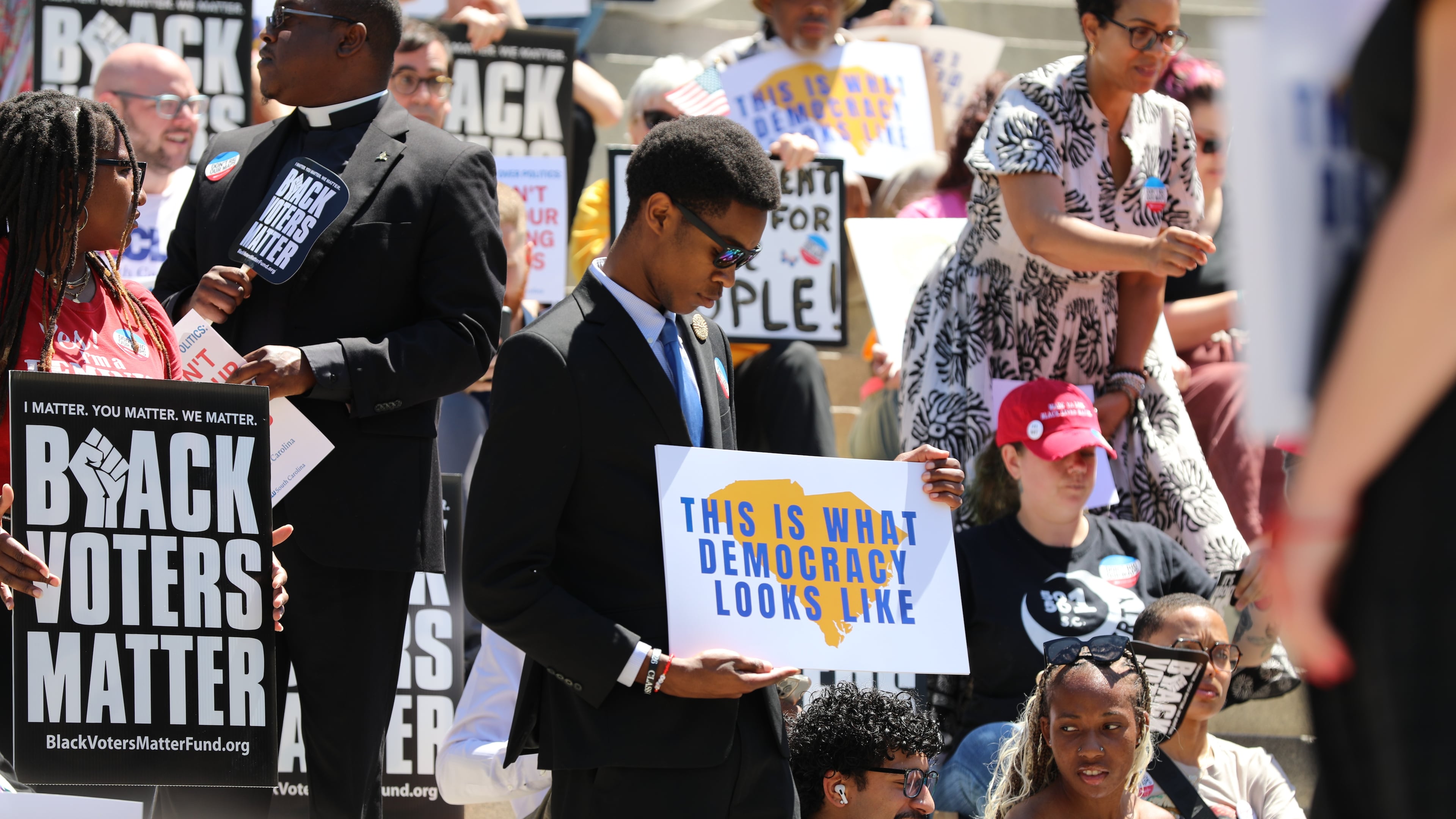 A protestor stands outside the South Carolina Statehouse on Thursday, May 14, 2026, in Columbia, S.C. (AP Photo/Jeffrey Collins)