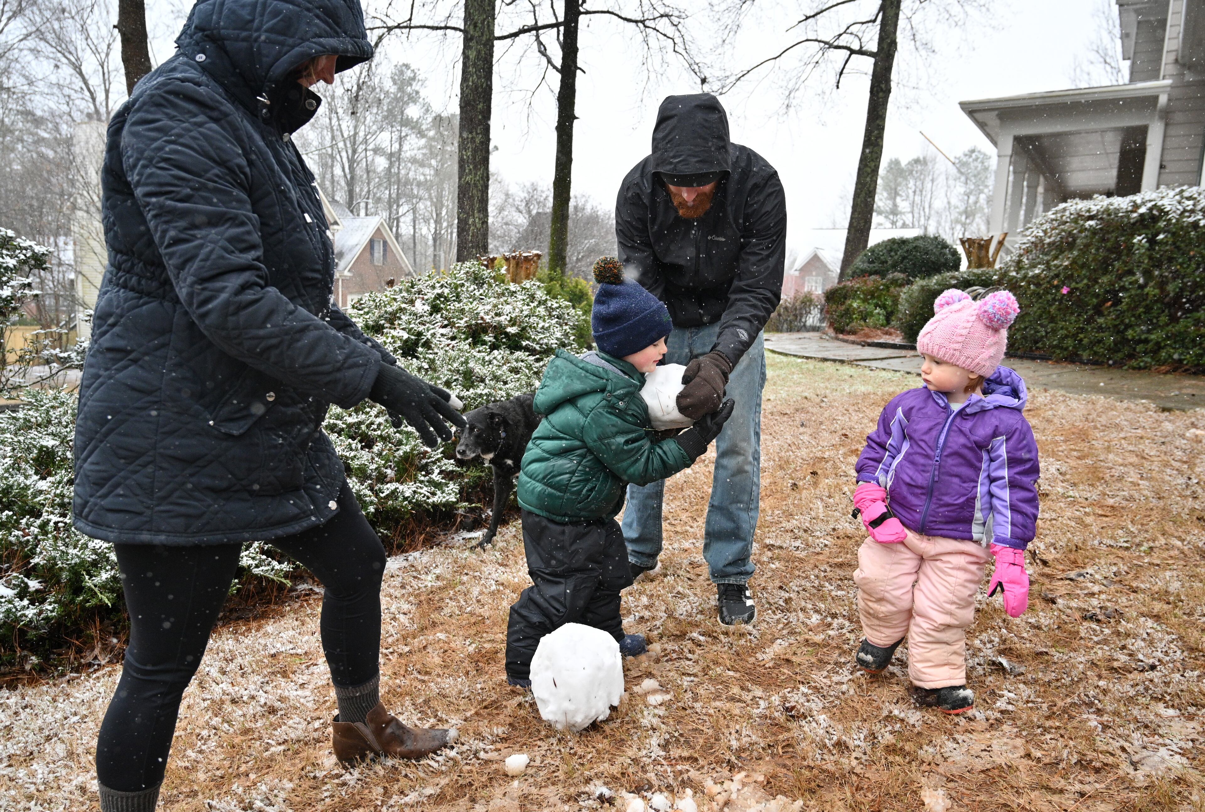 January 16, 2022 Lawrenceville - Jessica and Gurell Richie help their children Henry, 3, and Penny, 2, building a snowman at their front yard in Lawrenceville on Sunday, January 16, 2022. Snowfall continues to move south of I-285 and south Fulton and Coweta counties could see up to 2 inches of snow by Sunday evening. Major impacts near Lake Lanier and into the North Georgia mountains are being felt and certain spots could see up to 10 inches of snow. As of around noon, snow is moving through Troup and Coweta counties, as Fayette and Clayton counties still patiently wait for some flurries amidst the rain and some wintry mix. (Hyosub Shin / Hyosub.Shin@ajc.com)