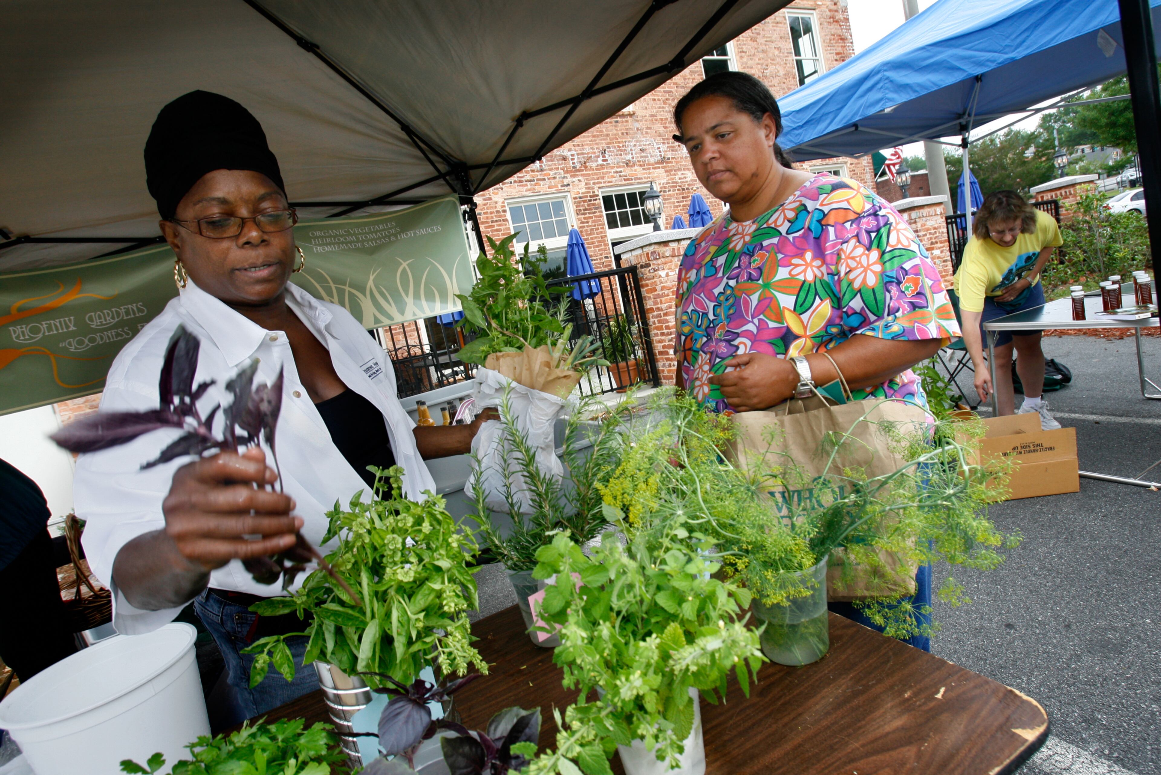 Gwendolyn Washington, left, of Phoenix Farms in Lawrenceville picks out some herbs for customer Sheryl Holmes right, of Lawrenceville at the Lawrenceville Farmers Market.