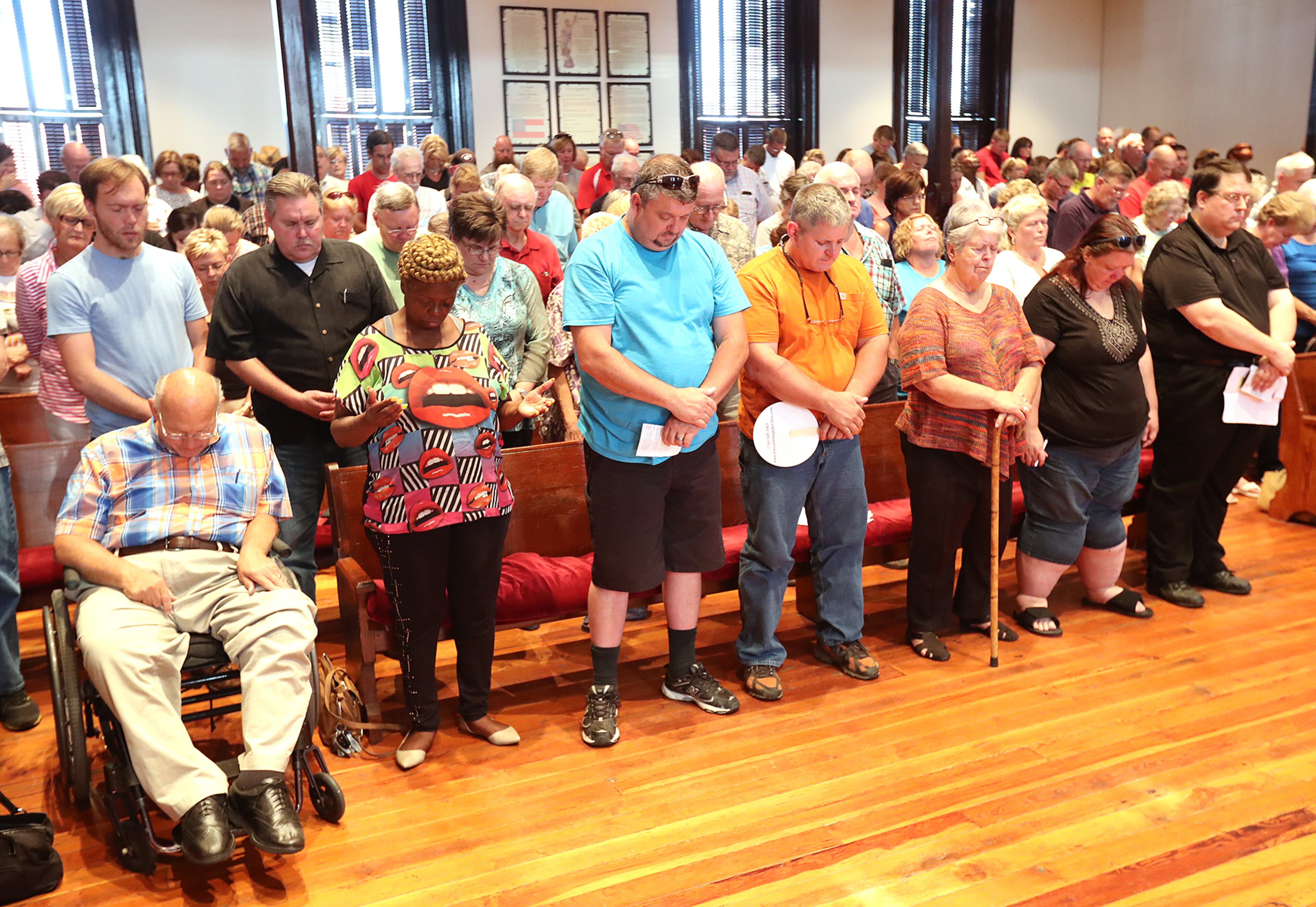 Residents bow their heads during an opening prayer before public comments on plans to build a mosque in Newton County. Curtis Compton /ccompton@ajc.com