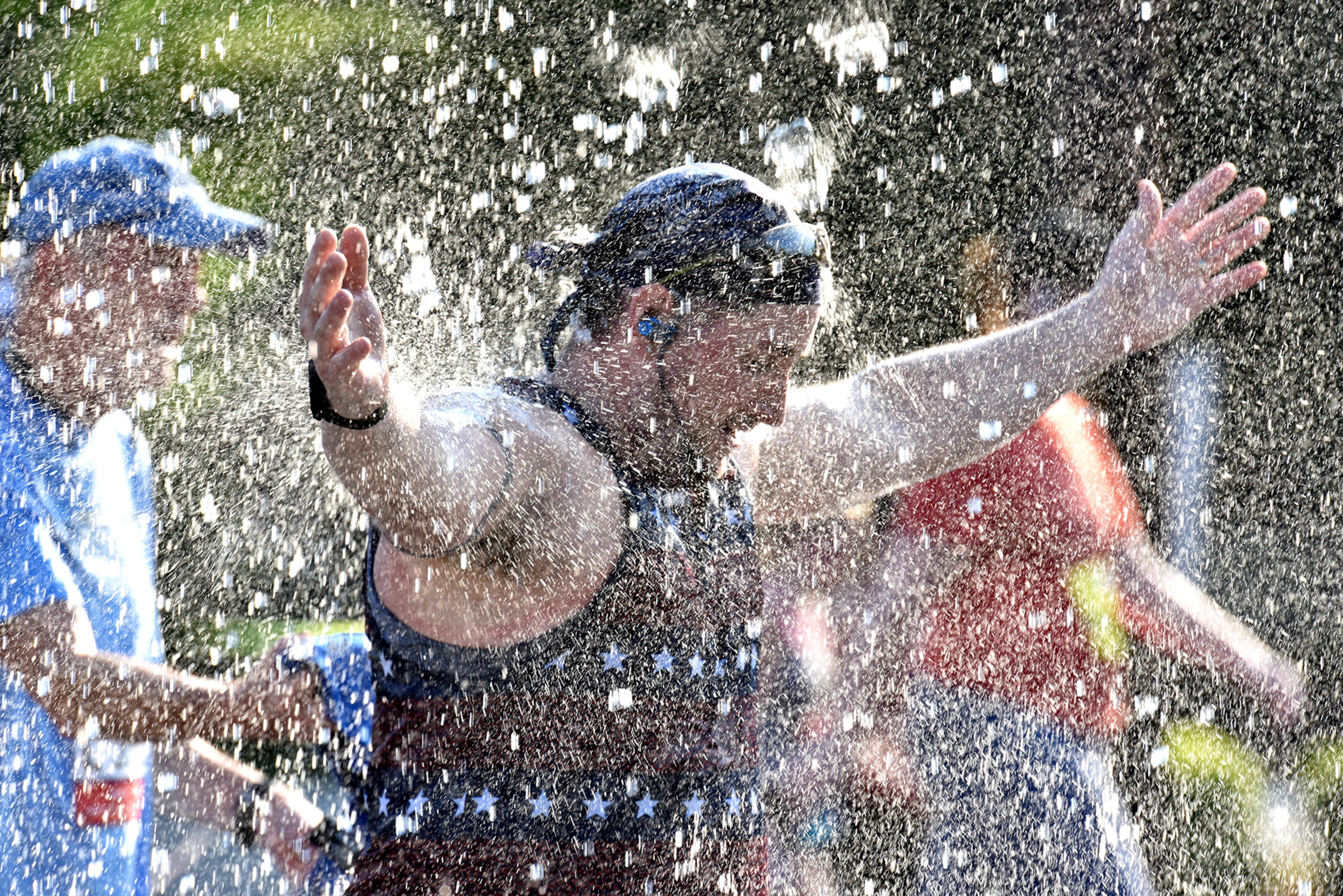 July 4, 2018 Atlanta - Runners cool off in a shower of water that refreshed them just before they approach Cardiac Hill during the AJC Peachtree Road Race on Wednesday, July 4, 2018. HYOSUB SHIN / HSHIN@AJC.COM