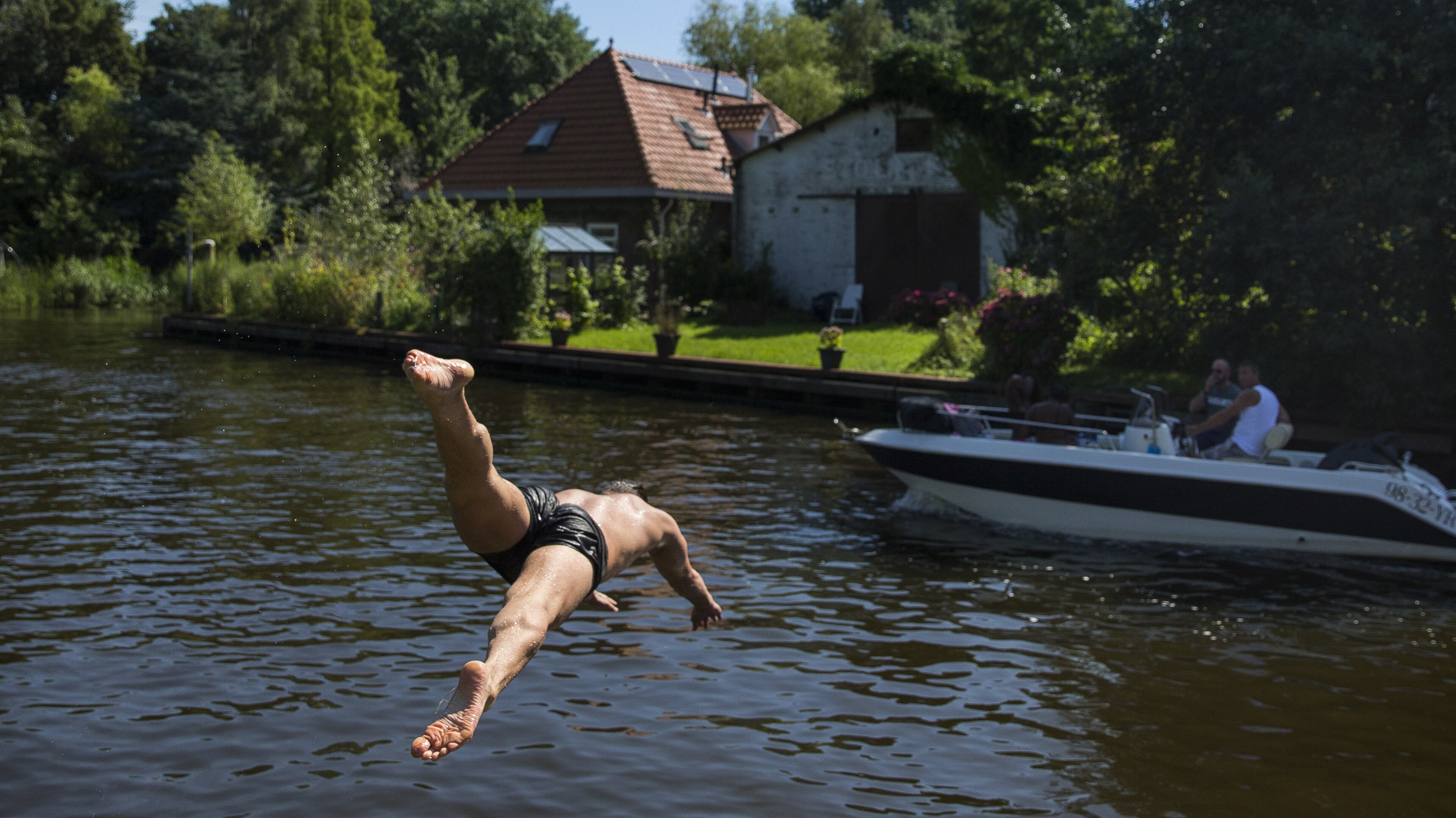 A man dives into the water in a quiet part of the Amsterdam North neighborhood, across the harbor from Amsterdam’s old city center, Aug. 23, 2016. A new tunnel paneled with blue-and-white Dutch tiles depicting old nautical scenes has helped solve an age-old problem of binding Amsterdam North more closely to the rest of the city. (Ilvy Njiokiktjien/The New York Times)