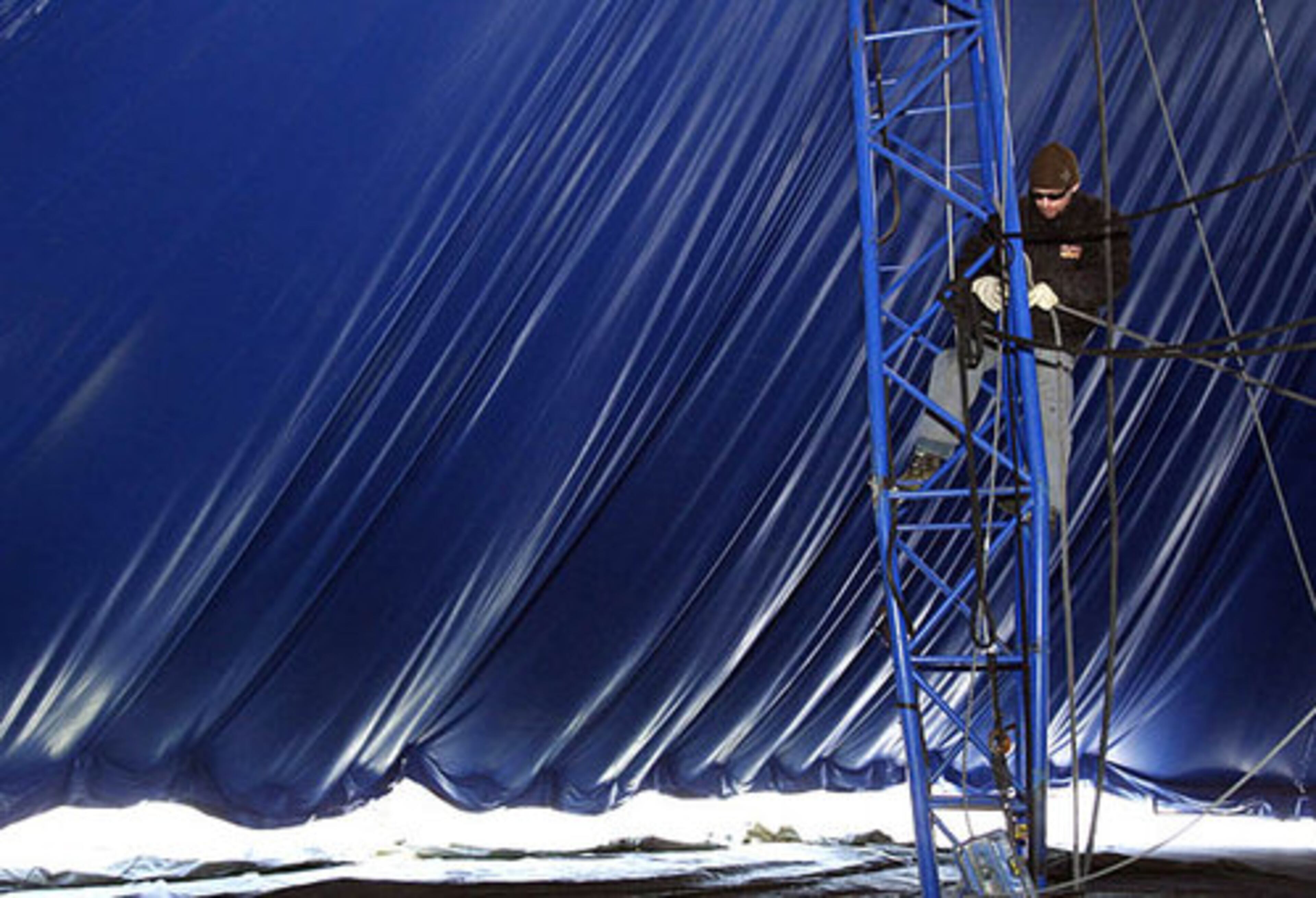 Crew member Akos Feher climbs up to set up ropes for the trapeze.