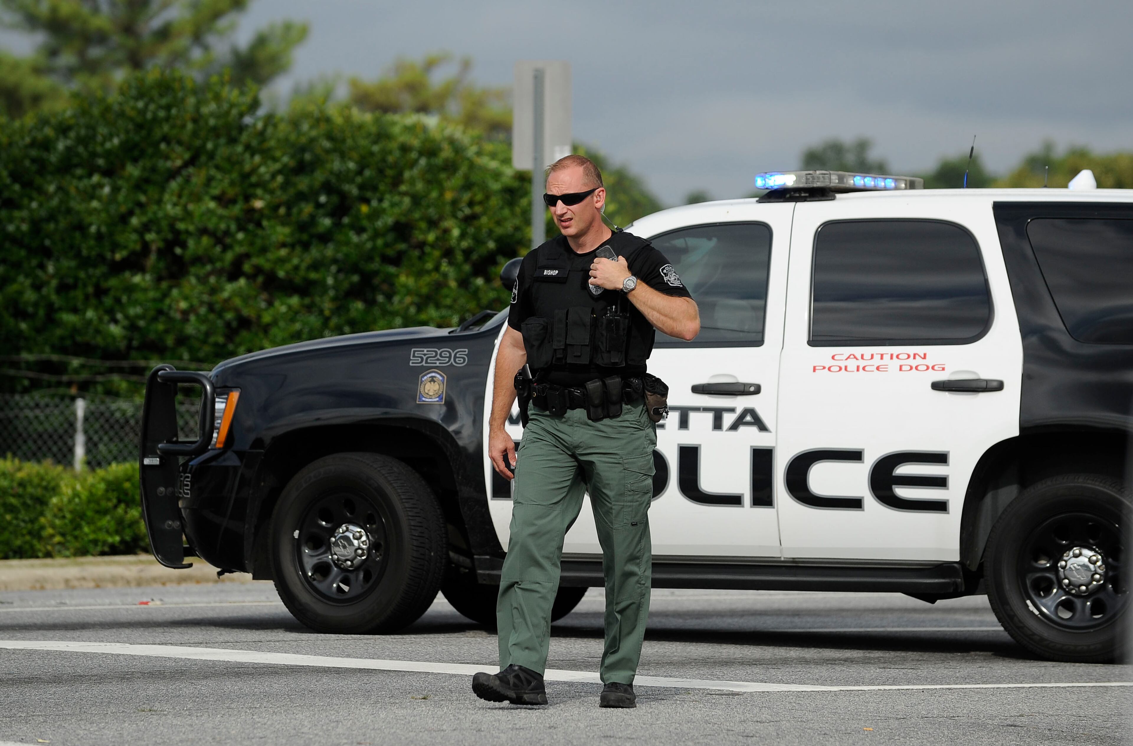 A Marietta police officer stops traffic during the morning commute on the busy U.S. Highway 41 while a motorcade transporting an American infected with the deadly Ebola virus from West Africa leaves Dobbins Air Reserve Base Tuesday, Sept. 9, 2014 in Marietta, Ga., for Emory University Hospital in Atlanta. (AP Photo/David Tulis)