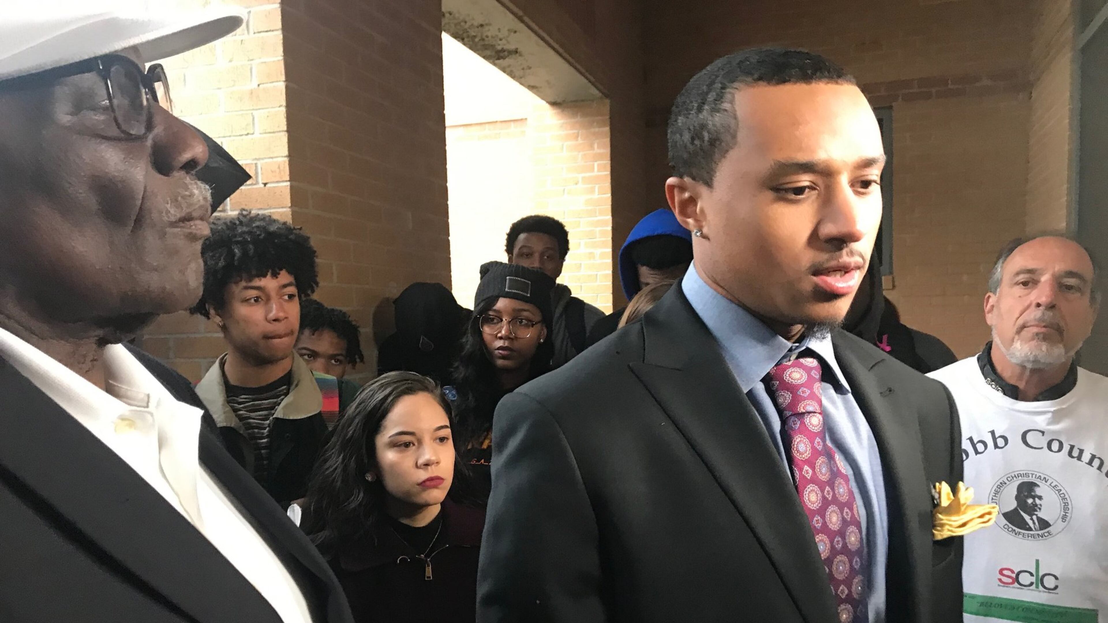 Students and supporters of Kennesaw State University student Elijah John (center) look on as he talks to reporters on Tuesday about a racist social media post he says targeted him. ERIC STIRGUS / ESTIRGUS@AJC.COM