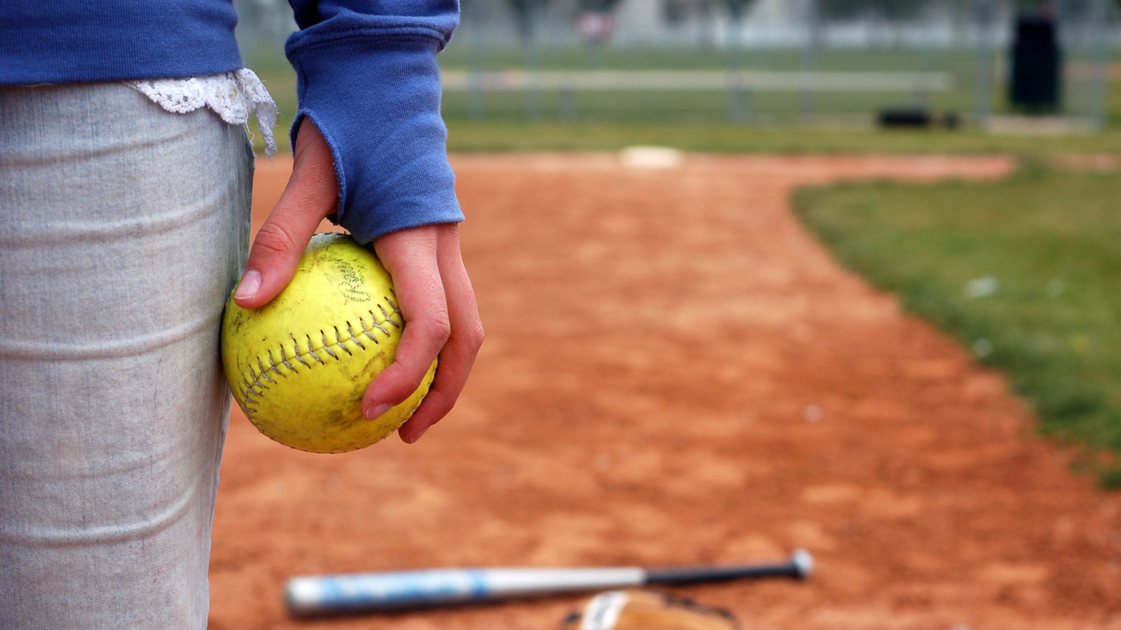 A girl holds a softball on the infield diamond.
