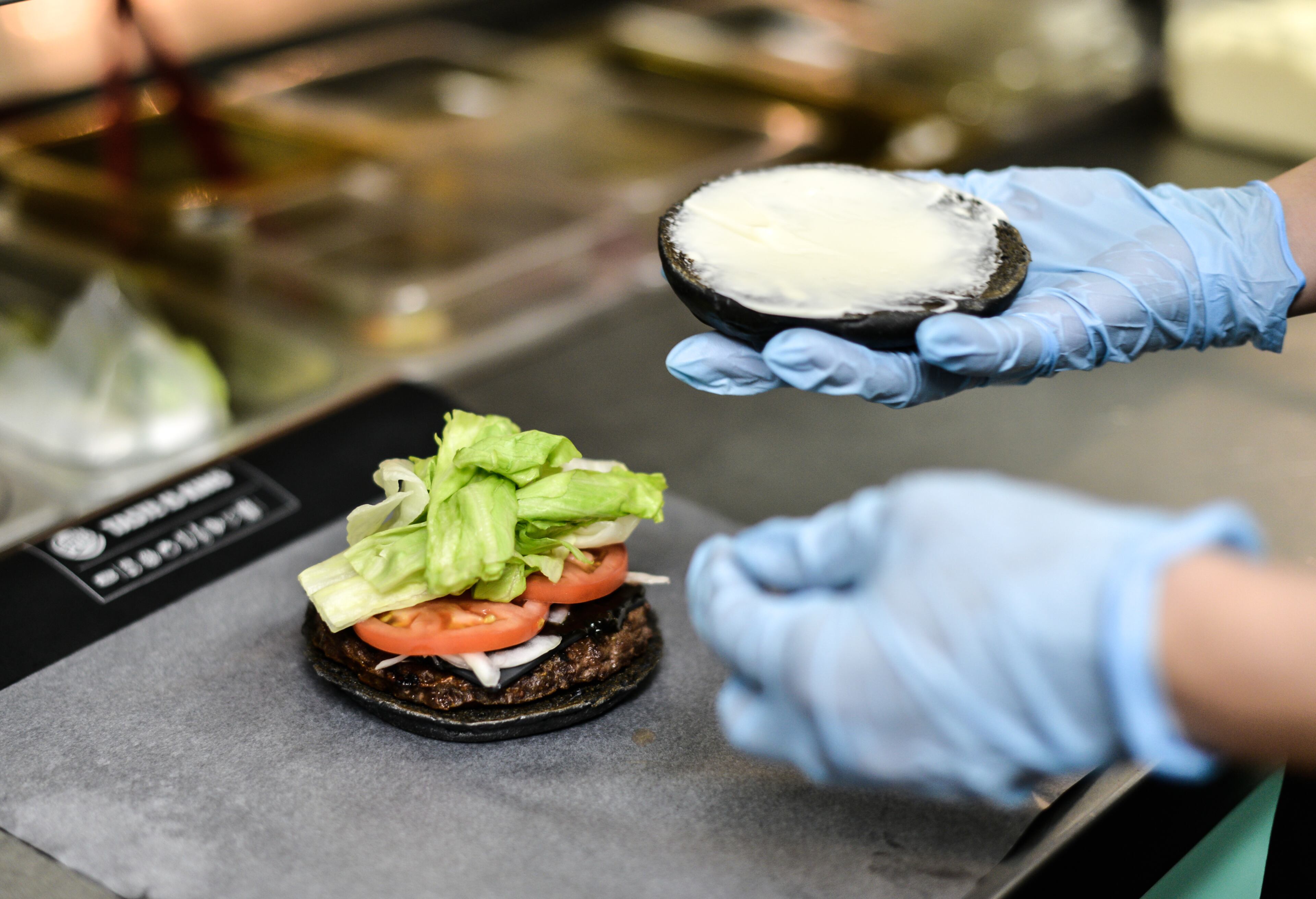 TOKYO, JAPAN - SEPTEMBER 18: A Burger King employee prepares a black burger at a company restaurant on September 18, 2014 in Tokyo, Japan. The black burgers, one a Kuro Pearl at 480 yen, has black buns, cheese smoked with bamboo charcoal and black sauce made of squid ink. The other, the Kuro Diamond at 690 yen, comes also with lettuce, tomato, onion and mayonnaise. The burgers are available from September 19 through early November in Burger King restaurants throughout Japan. (Photo by Keith Tsuji/Getty Images)