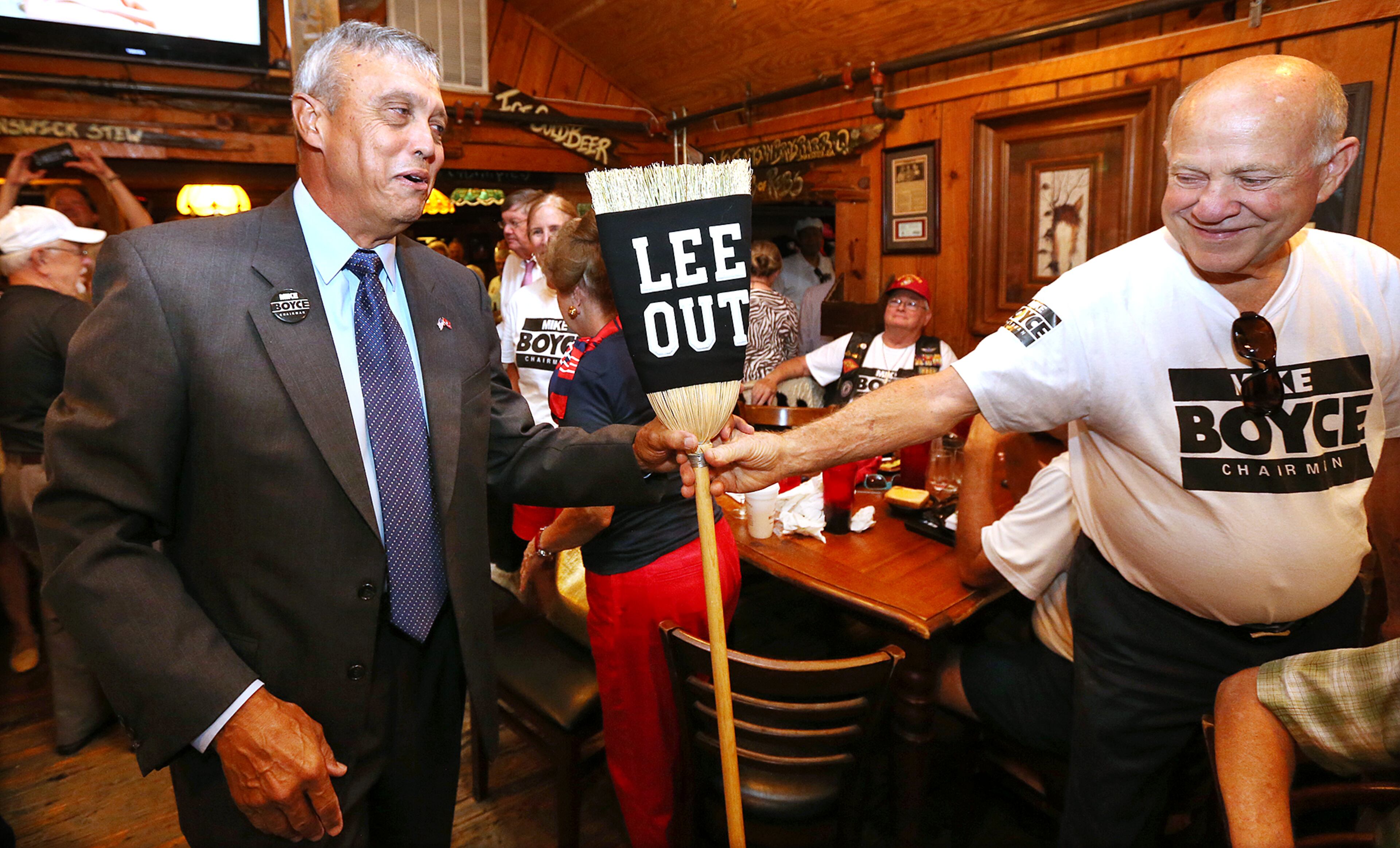 Supporter Howard Wolf hands Mike Boyce a broom as he arrives at his watch party at Williams Brothers BBQ. He defeated incumbent Tim Lee on Tuesday, July 26, 2016. Curtis Compton /ccompton@ajc.com