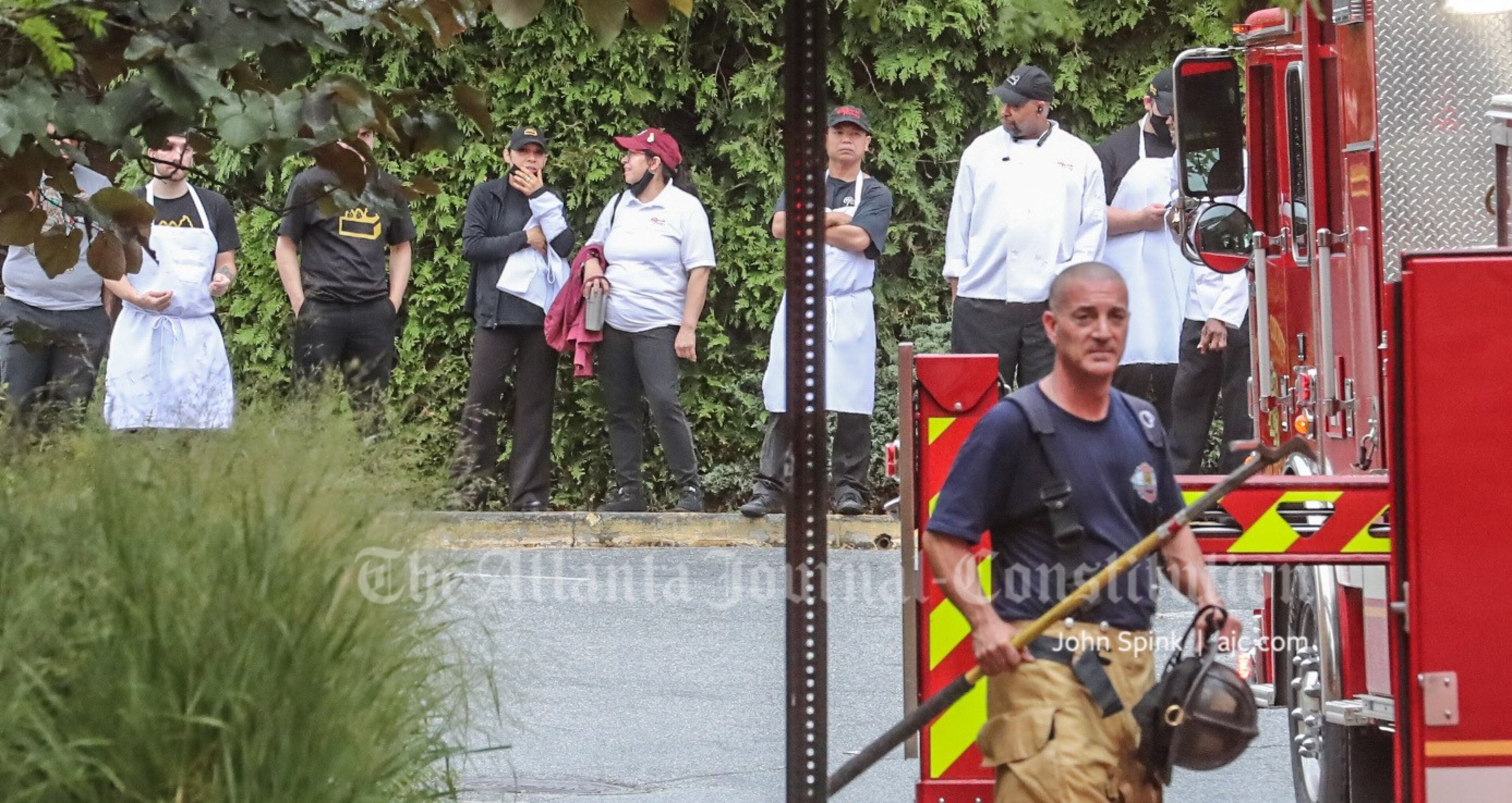 Employees of the Cheesecake Factory wait outside Perimeter Mall following a kitchen fire Tuesday morning.