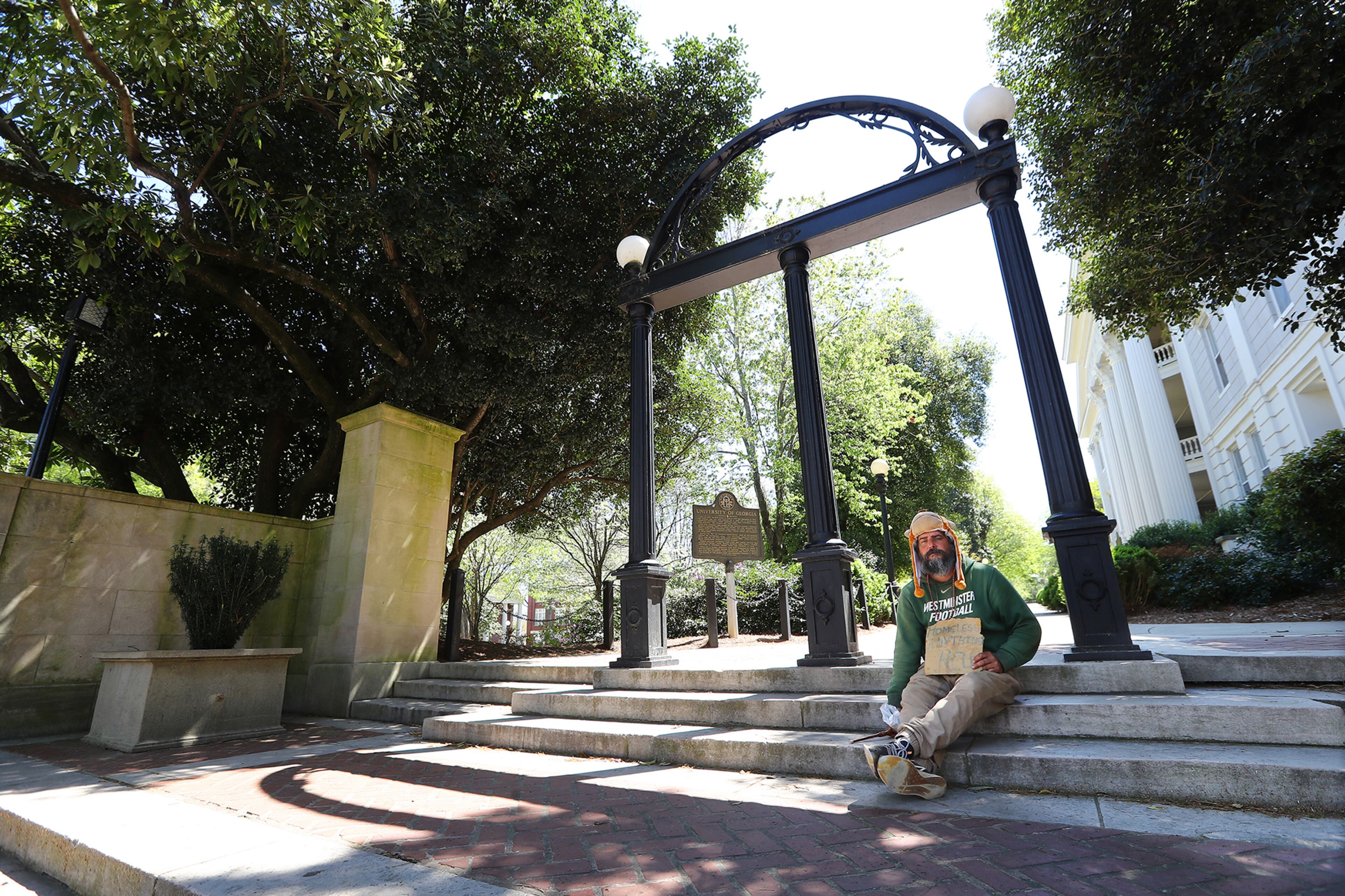 April 2, 2020 Athens: Passersby are few and far between as homeless man Robert Leseueur barely raises enough for a Chic-fil-A sandwich while waiting for handouts in front of the normally bustling University of Georgia Arch in downtown Athens on Thursday, April 2, 2020. Leseueur said âÃúitâÃôs been really slow itâÃôs like a ghost town hereâÃù. A mandatory shelter in place has been in effect in Athens-Clarke County long before many metro Atlanta towns took similar steps and the university is closed down. Curtis Compton ccompton@ajc.com