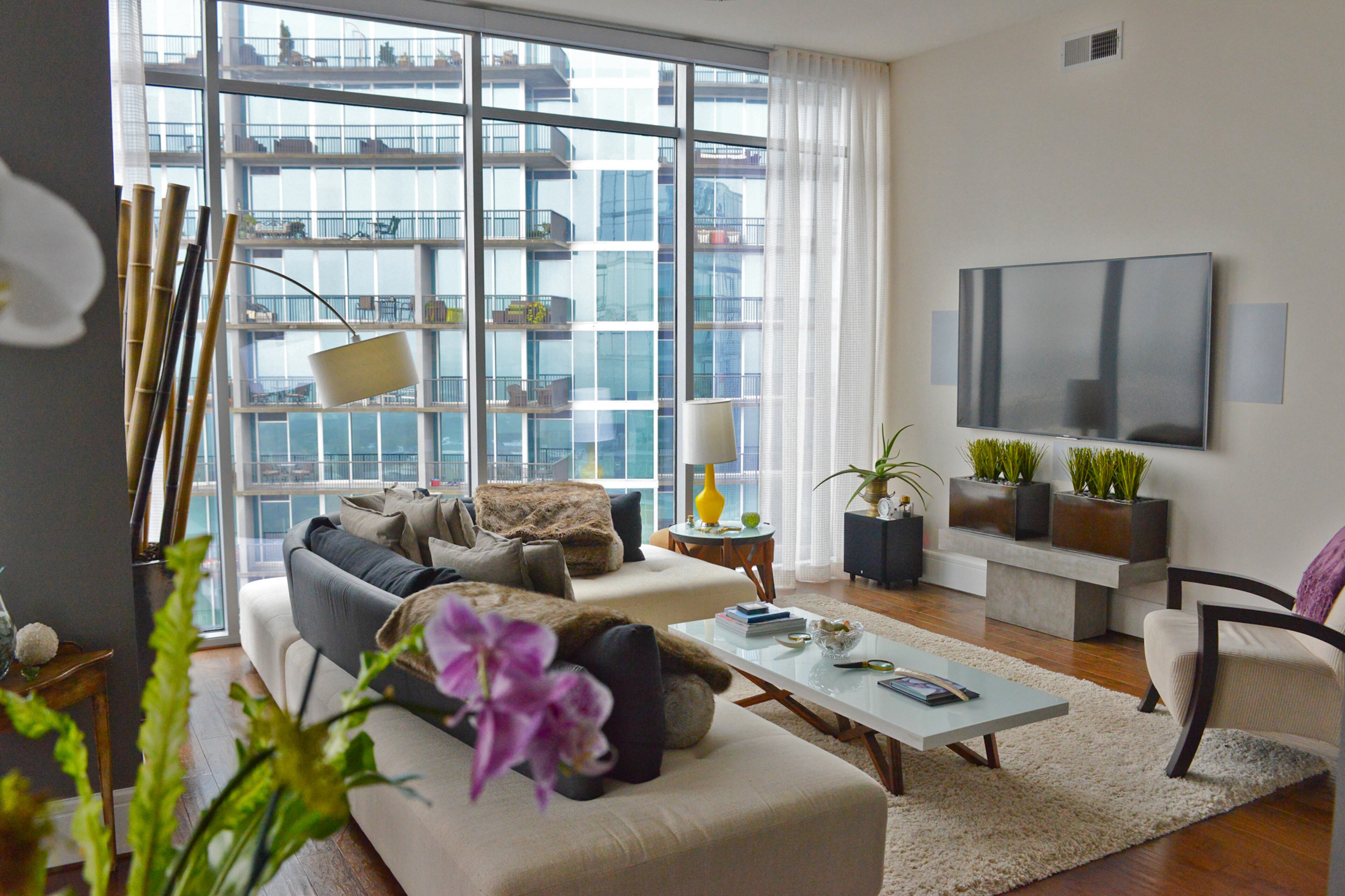 The 36th-floor condo's living room features modern pieces including a sectional from By Design Furniture, and floor lamp and table (underneath the TV) from CB2, also in Midtown Atlanta. The coffee table is a find from The Dump. Text by Lori Johnston and Keith Still/Fast Copy News Service