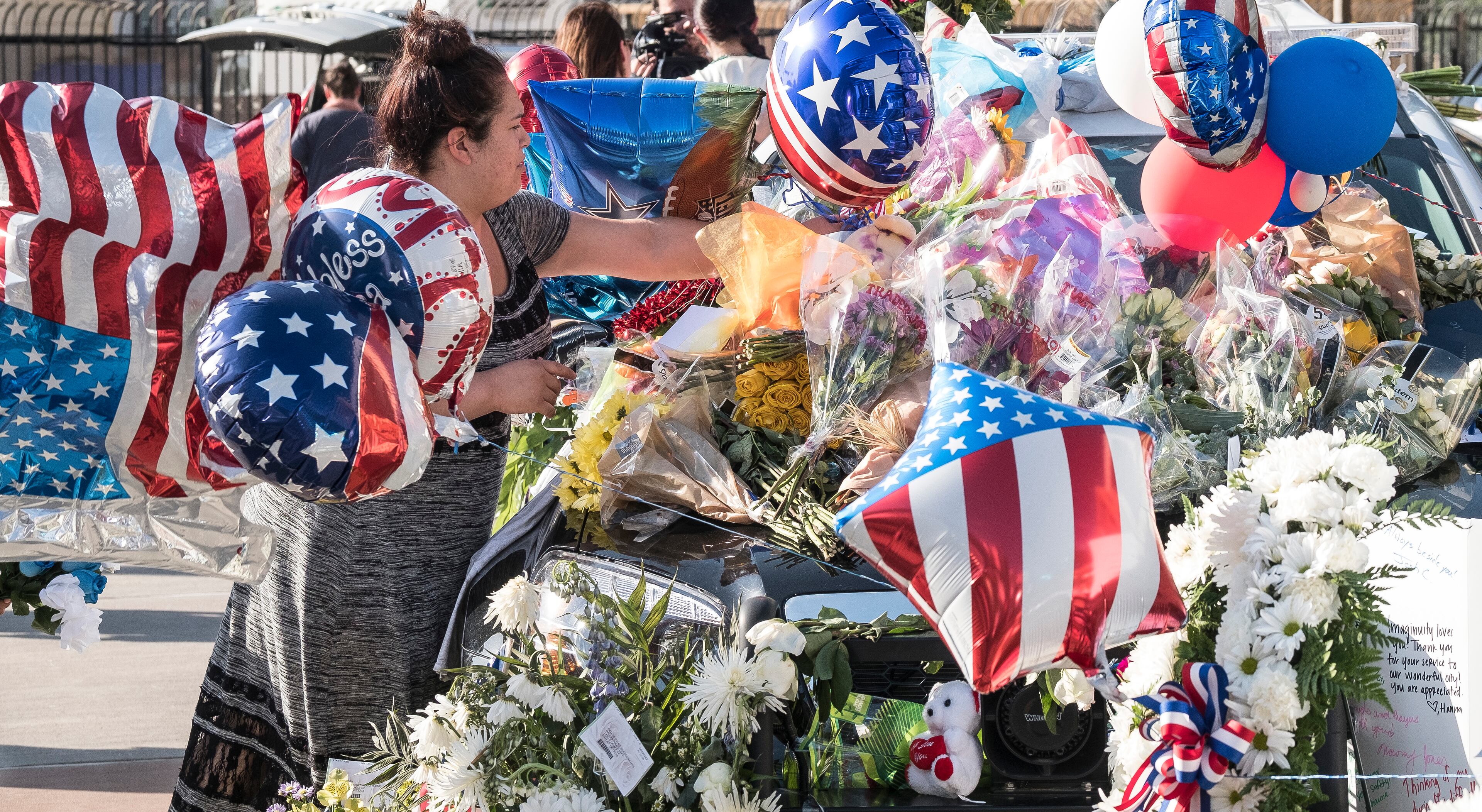 July 8, 2016 - Salena Solis, of Dallas, places flowers on a patrol care paying respect at a memorial of flowers, gifts and cards placed on Dallas patrol cars in front of the Dallas Police department headquarters in Dallas, Texas, on Friday, July 8, 2016. Five officers were killed, six officers wounded along with two civilians were shot by suspected sniper Micah Johnson. RODOLFO GONZALEZ / AUSTIN AMERICAN-STATESMAN