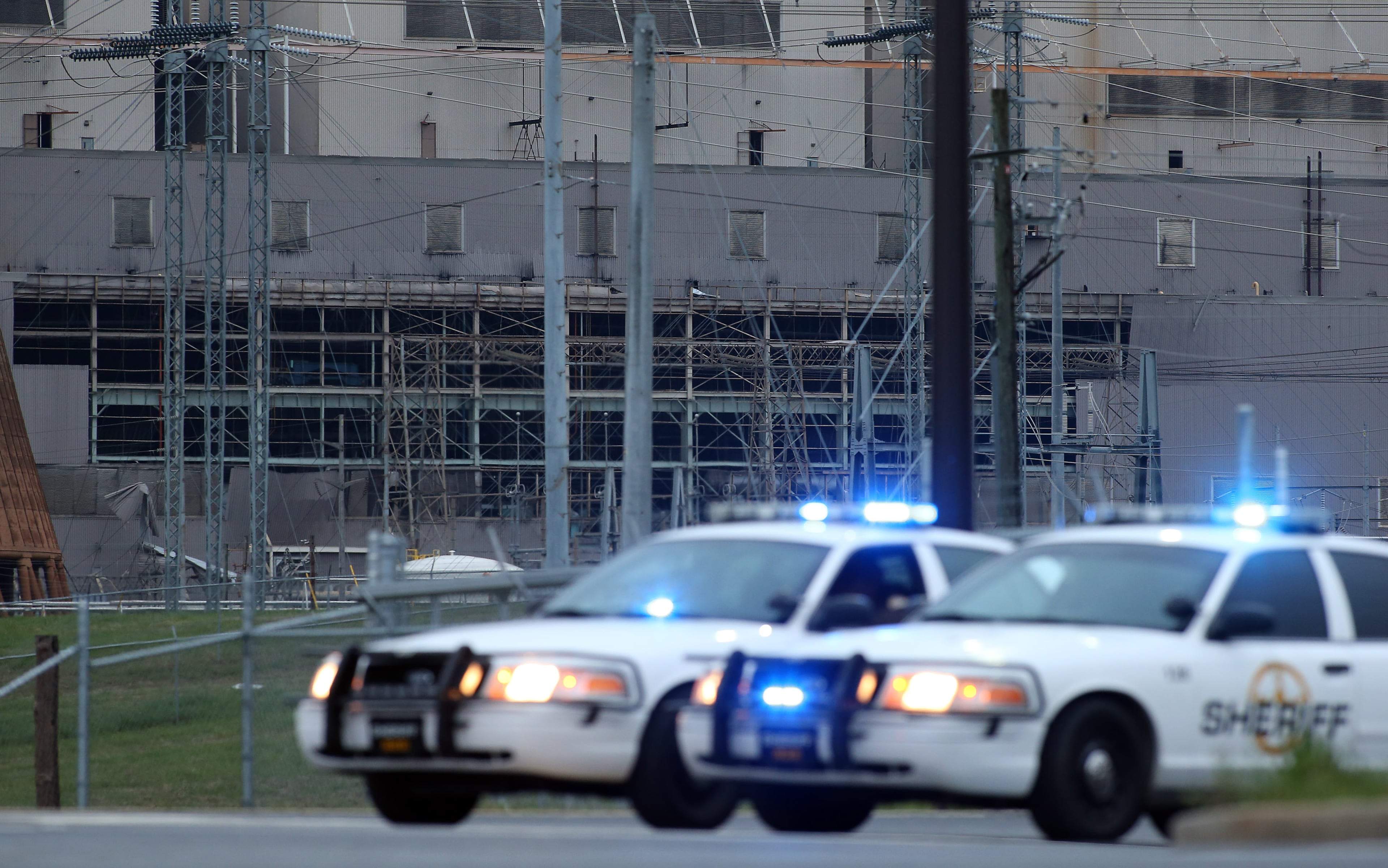 Two sheriff's cars guard the entrance to Georgia Power's Plant Bowen in Cartersville on Thursday evening, April 4, 2013, after an explosion occurred earlier in the day. The side of one of the buildings, seen behind the cars, blew open in the explosion, which caused minor injuries.
