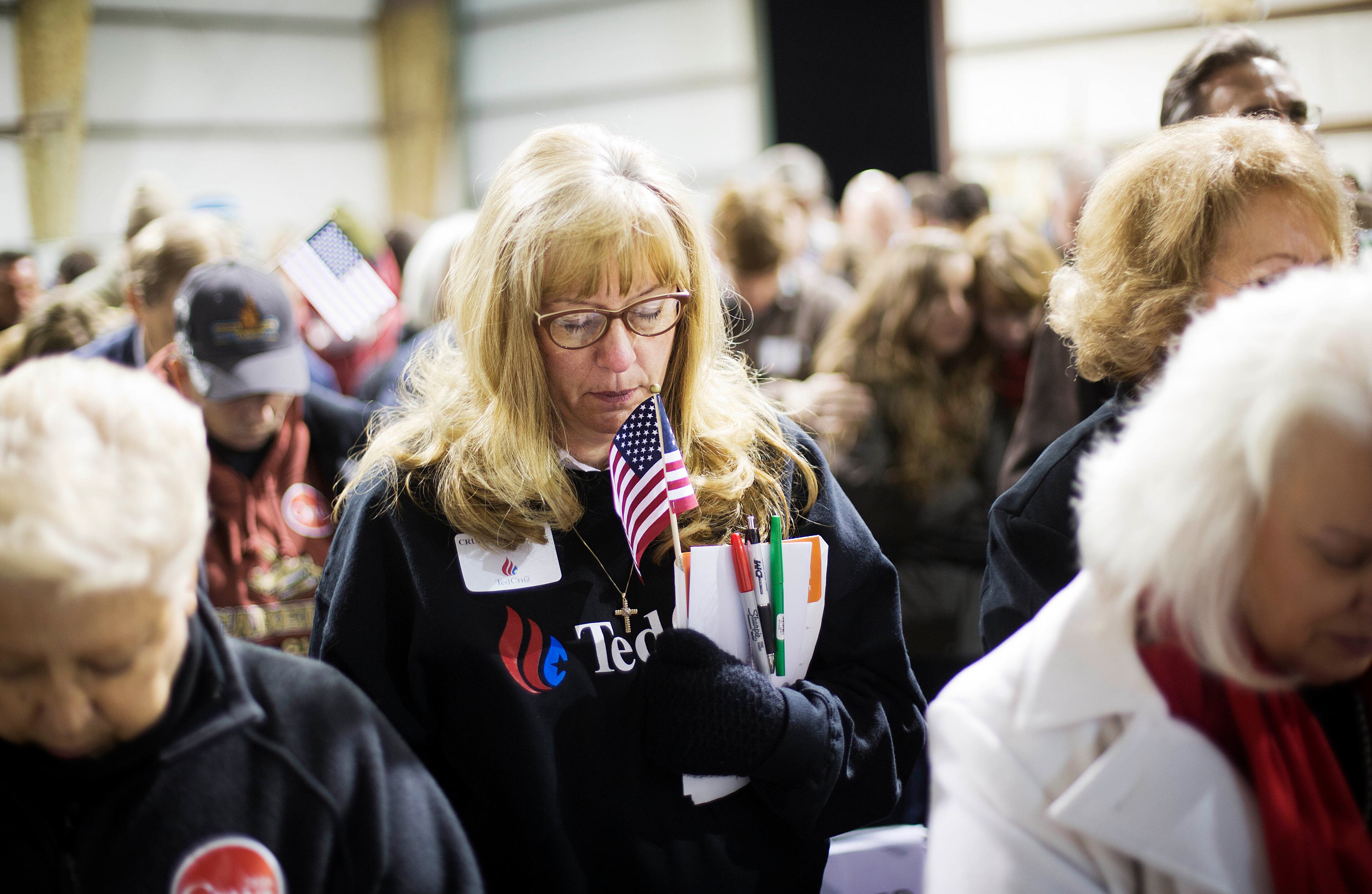A member of the crowd bows her head during a moment of prayer before Republican presidential candidate, Sen. Ted Cruz, R-Texas, speaks at a campaign event in an airport hanger Friday, Dec. 18, 2015, in Kennesaw, Ga. (AP Photo/David Goldman)