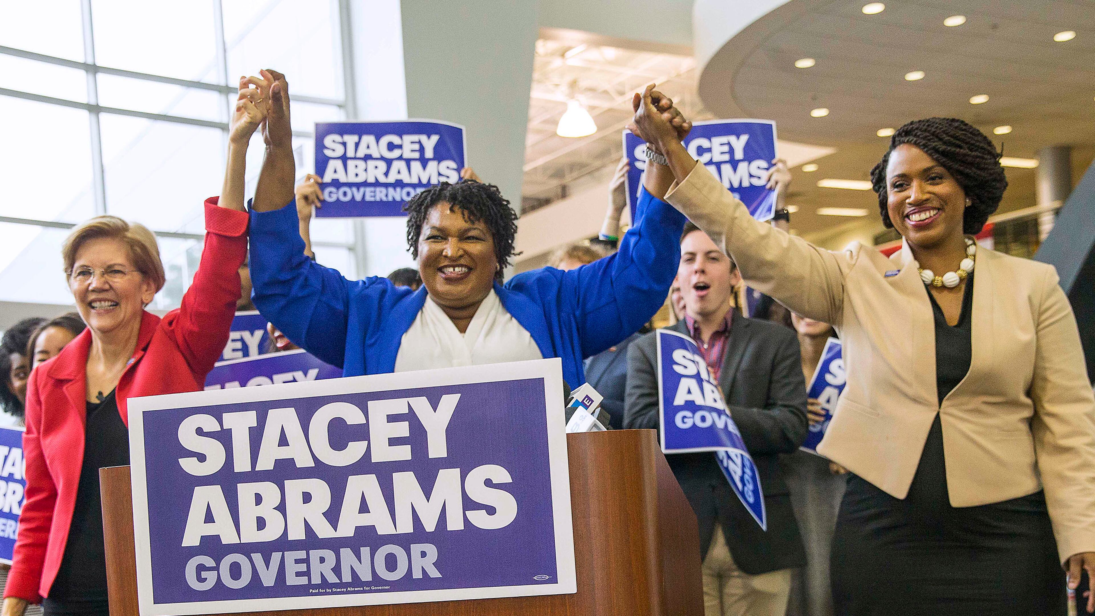 Democratic gubernatorial candidate Stacey Abrams links hands with U.S. Sen. Elizabeth Warren of Massachusetts (left) and Democratic congressional candidate Ayanna Pressley (right) during a rally at Clayton State University in Morrow on Tuesday. ALYSSA POINTER/ALYSSA.POINTER@AJC.COM