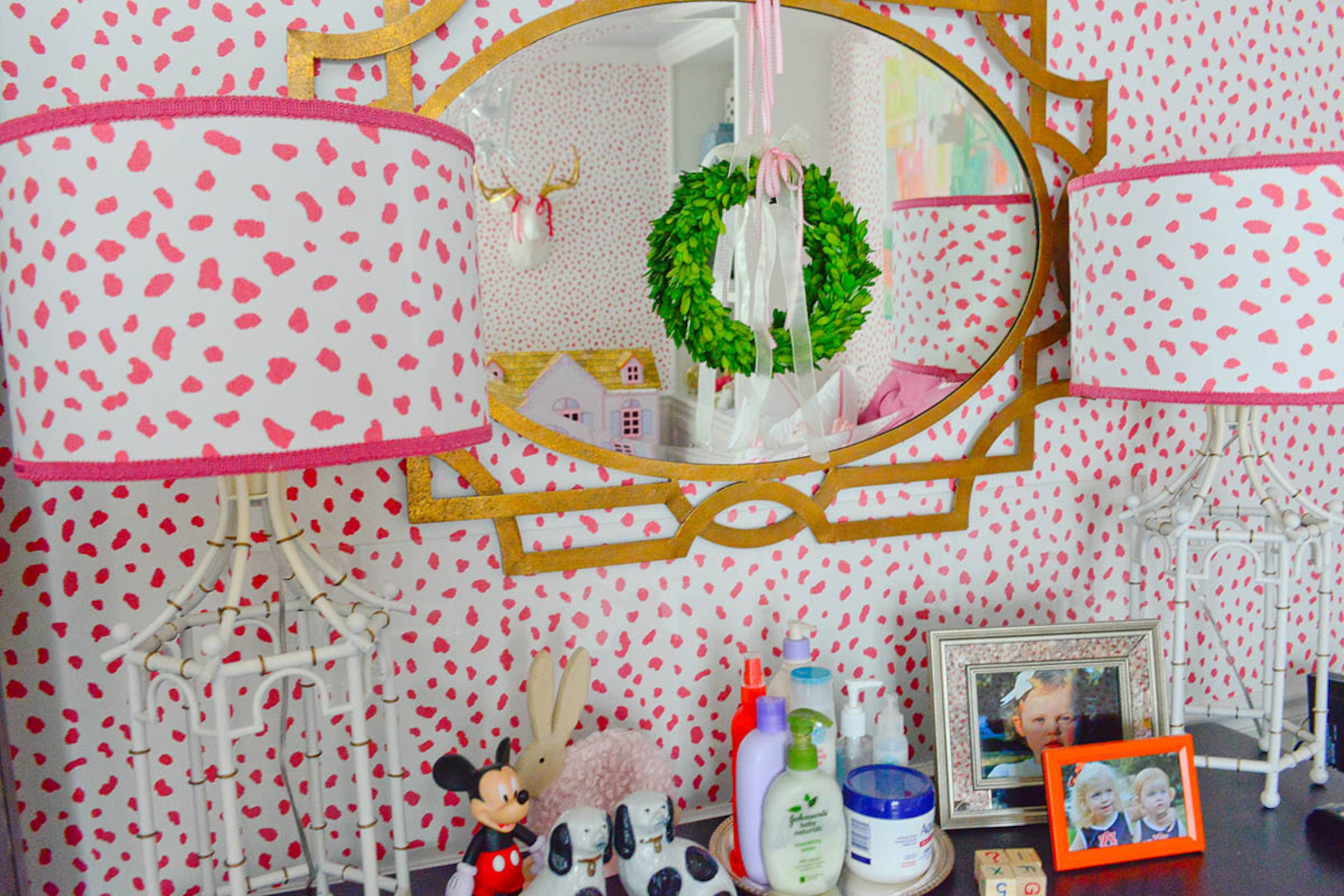 Wallpaper in the Tanzania pattern by Thibaut gives Caroline's bedroom a spirited backdrop. Katie Luepke took lamps from HomeGoods and used scraps of leftover wallpaper to cover the original black lampshades. Then she placed them on either side of a geometric mirror from Wisteria, making a stylish dresser display for her daughter's room.