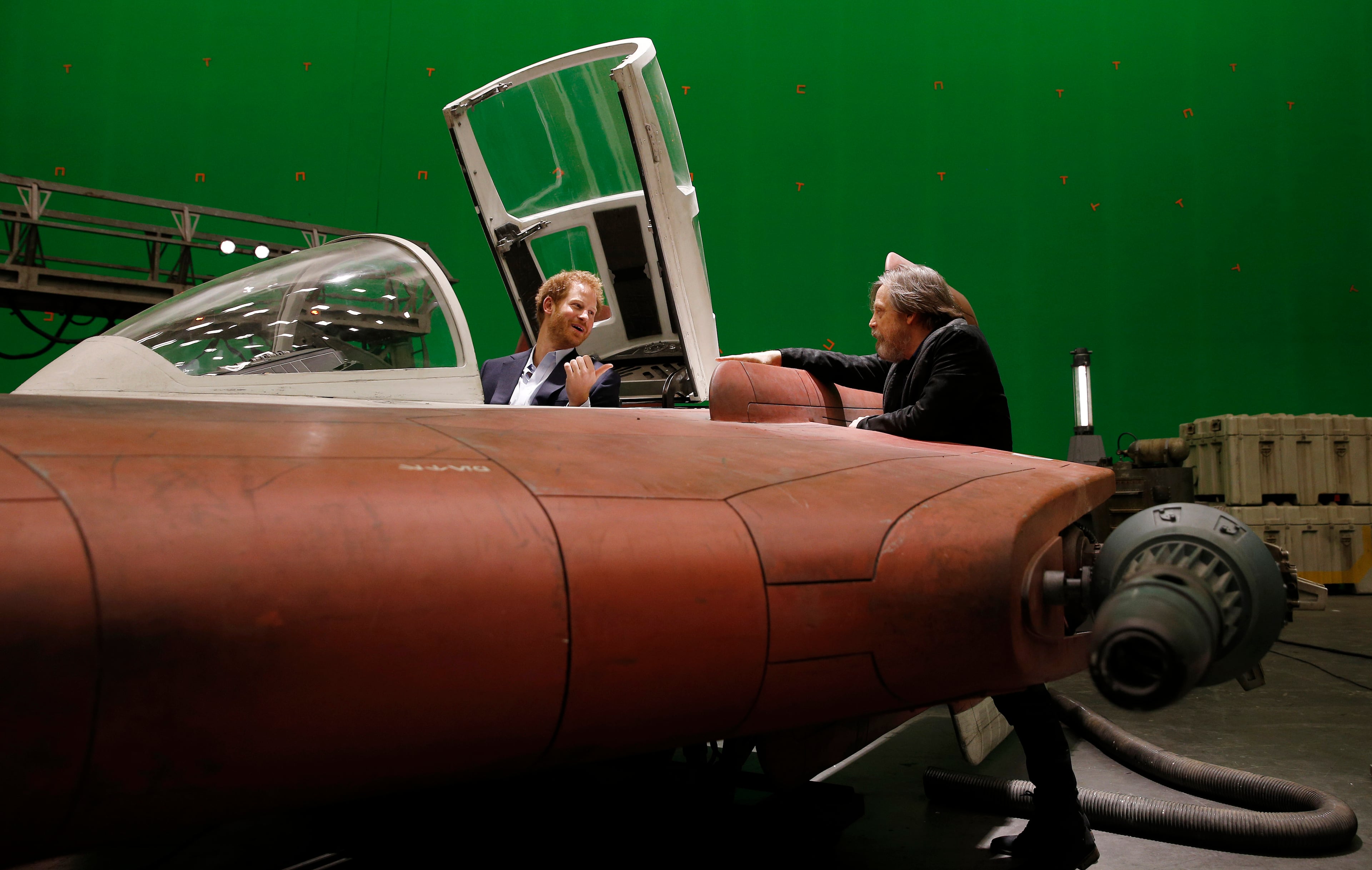 IVER HEATH, ENGLAND - APRIL 19: Prince Harry (L) sits in an A-wing fighter as he talks with US actor Mark Hamill during a tour of the Star Wars sets at Pinewood studios on April 19, 2016 in Iver Heath, England. Prince William and Prince Harry are touring Pinewood studios to visit the production workshops and meet the creative teams working behind the scenes on the Star Wars films. (Photo by Adrian Dennis-WPA Pool/Getty IMages)