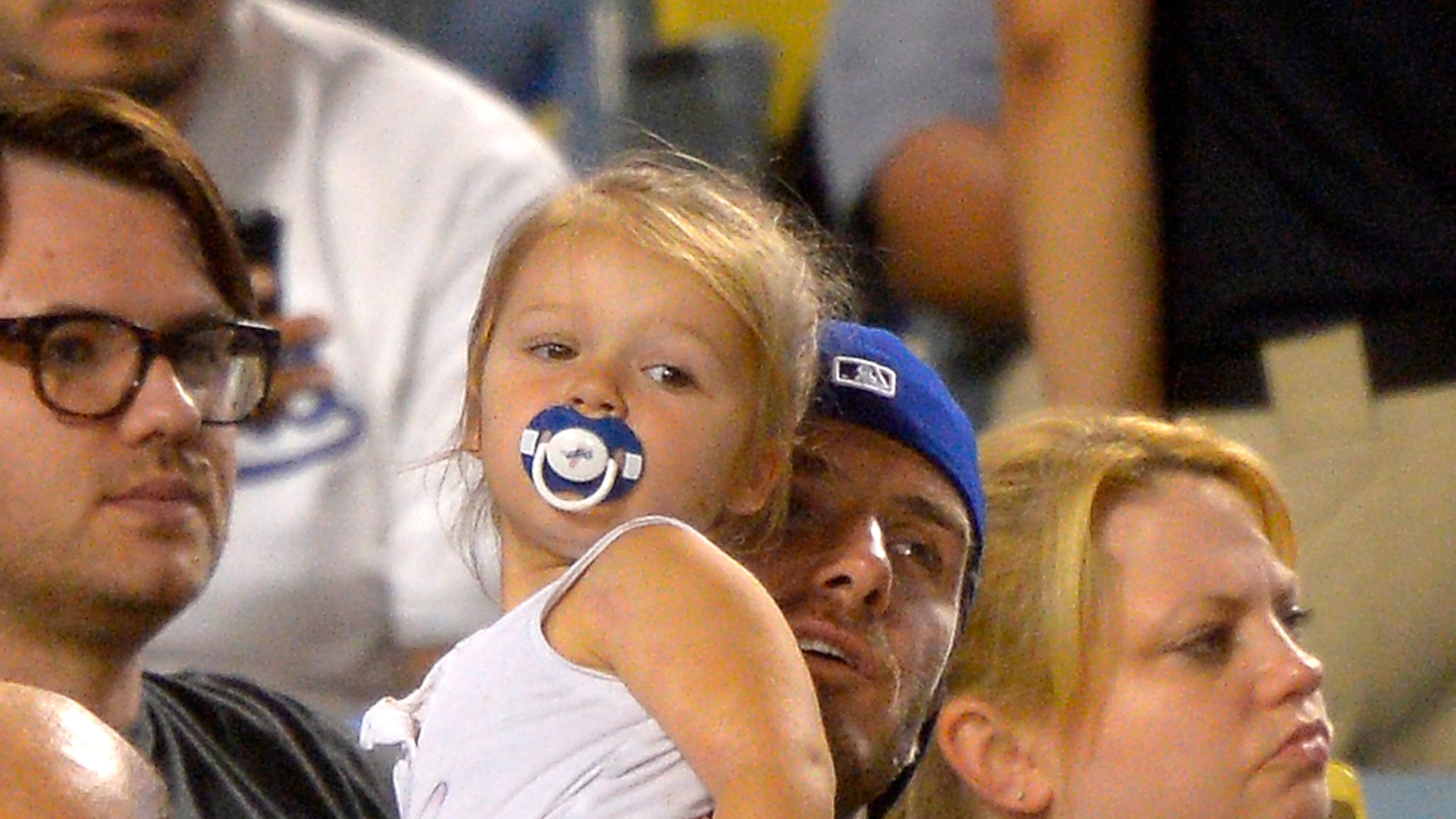 Retired soccer player David Beckham holds his daughter Harper as they watch the Los Angeles Dodgers play the Chicago Cubs in their baseball game, Tuesday, Aug. 27, 2013, in Los Angeles. (AP Photo/Mark J. Terrill)