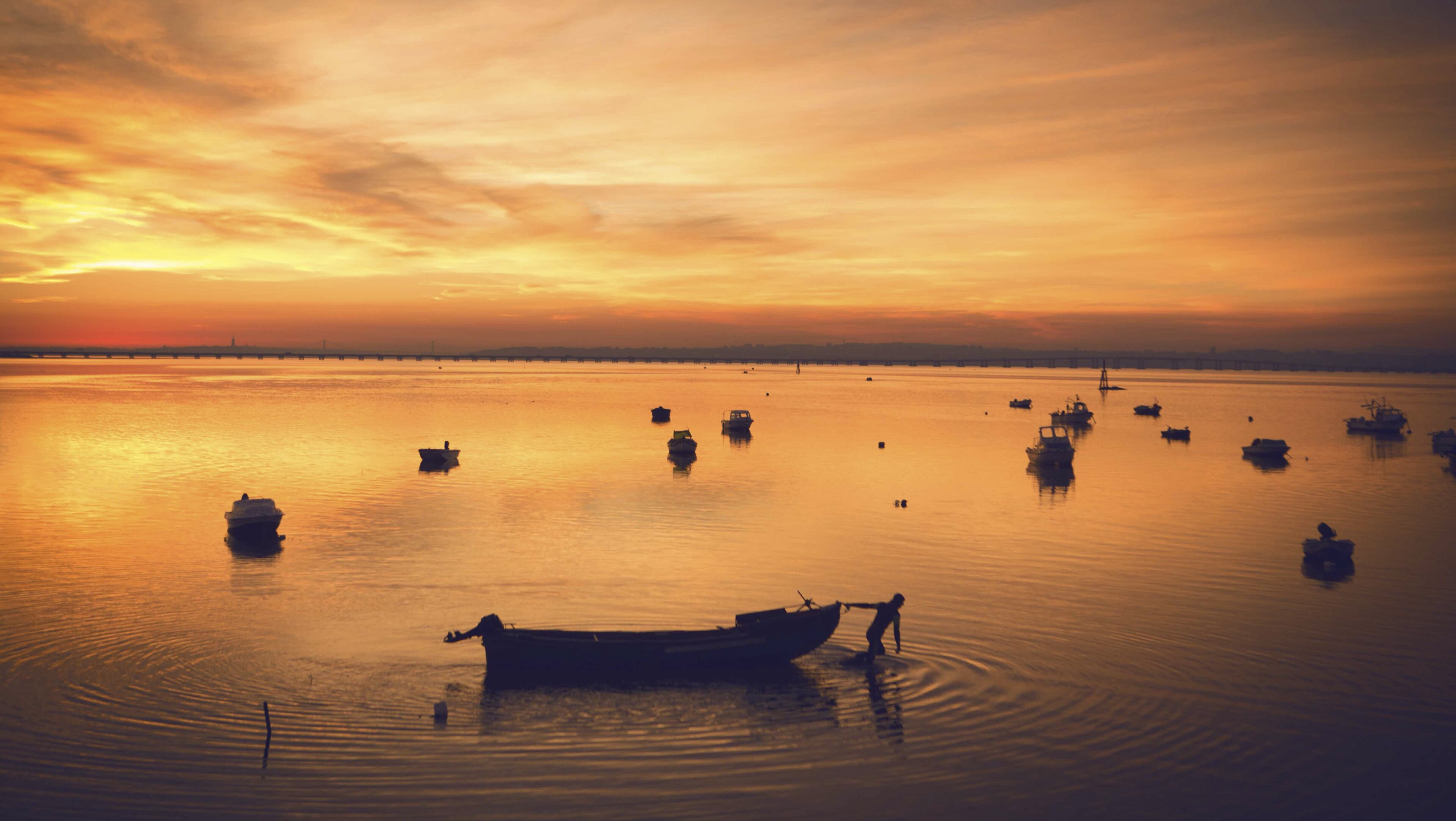 The sun sets over the Tagus River in Alcochete, Portugal, with Lisbon and the Vasco de Gama bridge, Europe’s longest, in the distance. The bridge is a gateway to the Alentejo region, a long-time budget vacation destination now taking its bow on the international stage as one of the top wine destinations in the world. (James Rajotte/The New York Times)