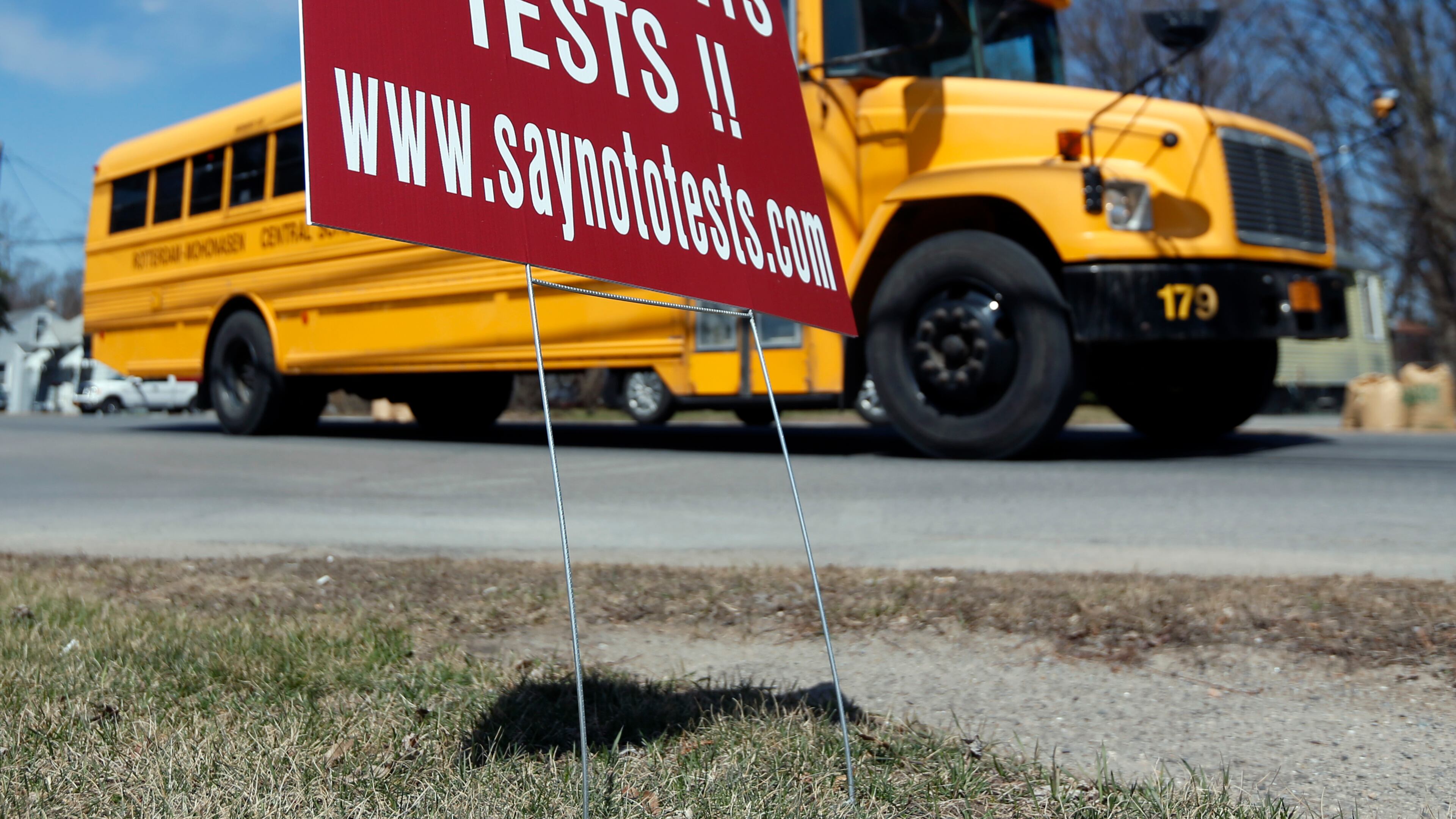 A school bus passes a sign encouraging parents to opt their children out of end-of-the-year state tests in New York. Georgia is about to launch a pilot program that would allow districts to create alternatives to its state exams, the Milestones.