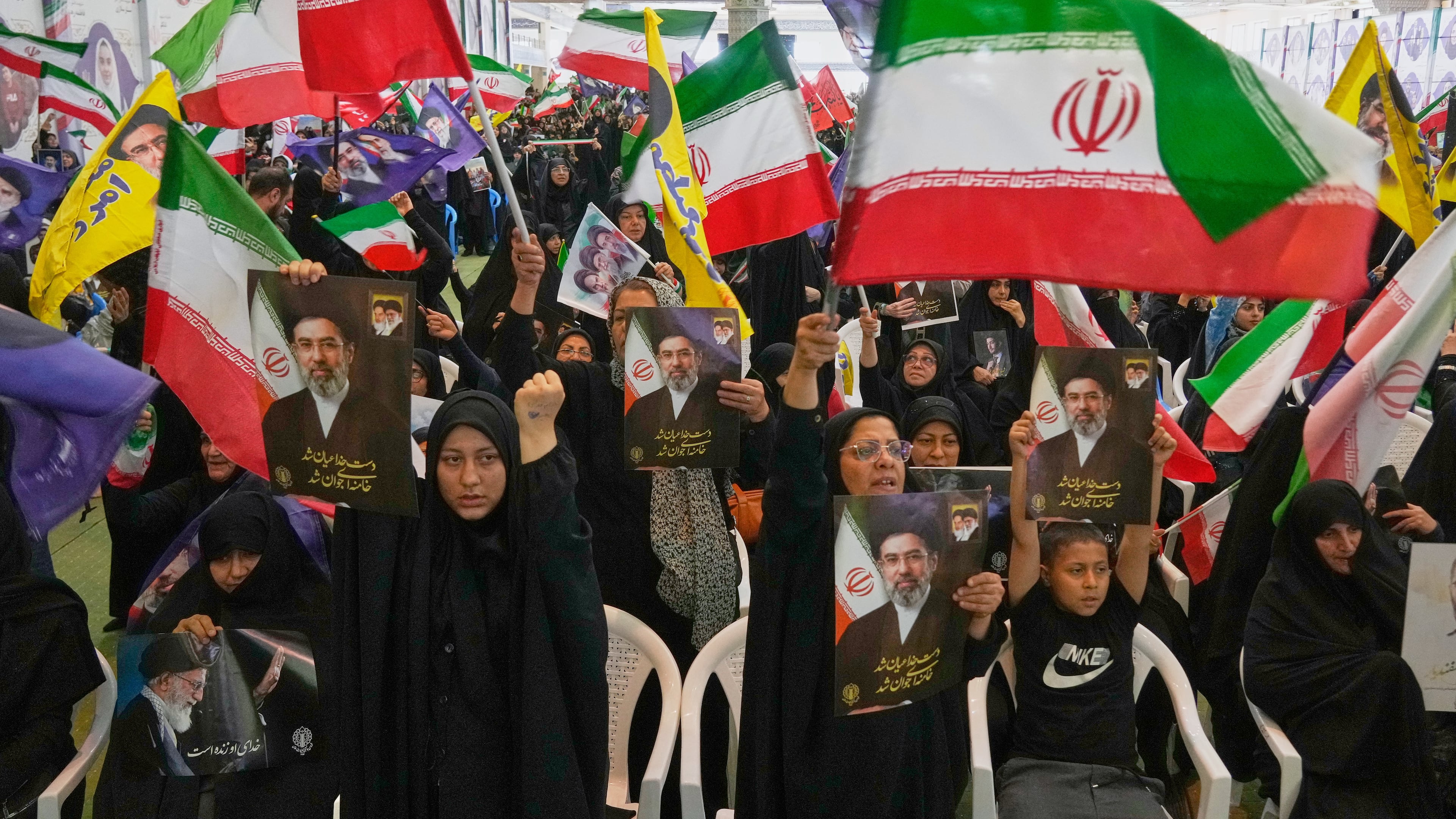 Government supporters hold Iranian flags and pictures of Iran's Supreme Leader, Ayatollah Mojtaba Khamenei, during a ceremony honoring the armed forces and those killed in the war with Israel and the U.S. at the Imam Khomeini Grand Mosque in Tehran, Iran, Sunday, May 24, 2026. (AP Photo/Vahid Salemi)