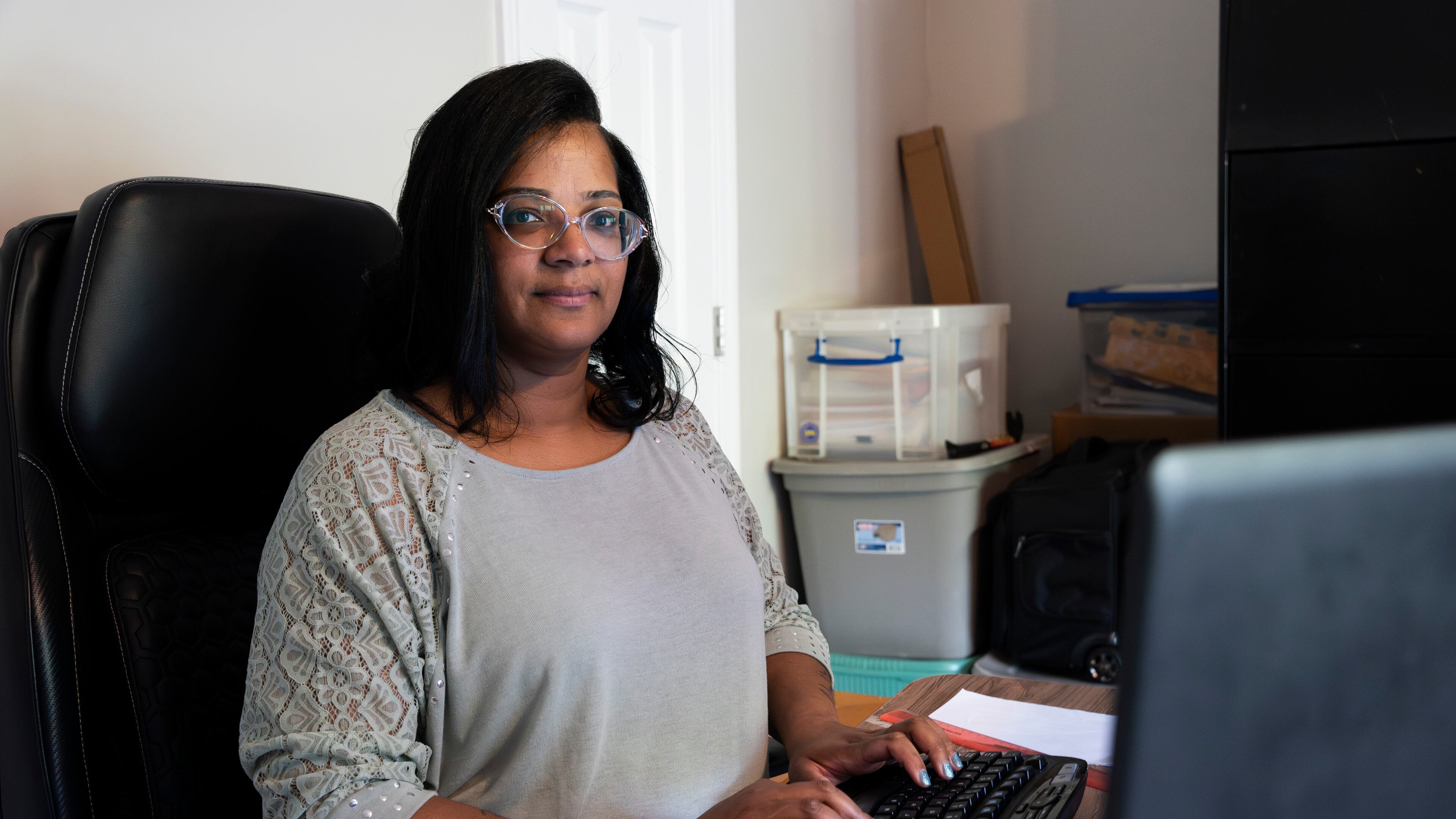 Tiesha Foreman poses for a portrait while checking her email at her home office in Douglasville, Georgia on Tuesday, April 16, 2024. Her job is harder now because, her lawyers say, she has become the victim of an insurance scam that has cost her thousands of dollars. She and her family have not gotten health care they needed because their insurance coverage was switched out from under them without their knowledge, she says. And not just once, but over and over. (PHOTO by Olivia Bowdoin for the AJC).