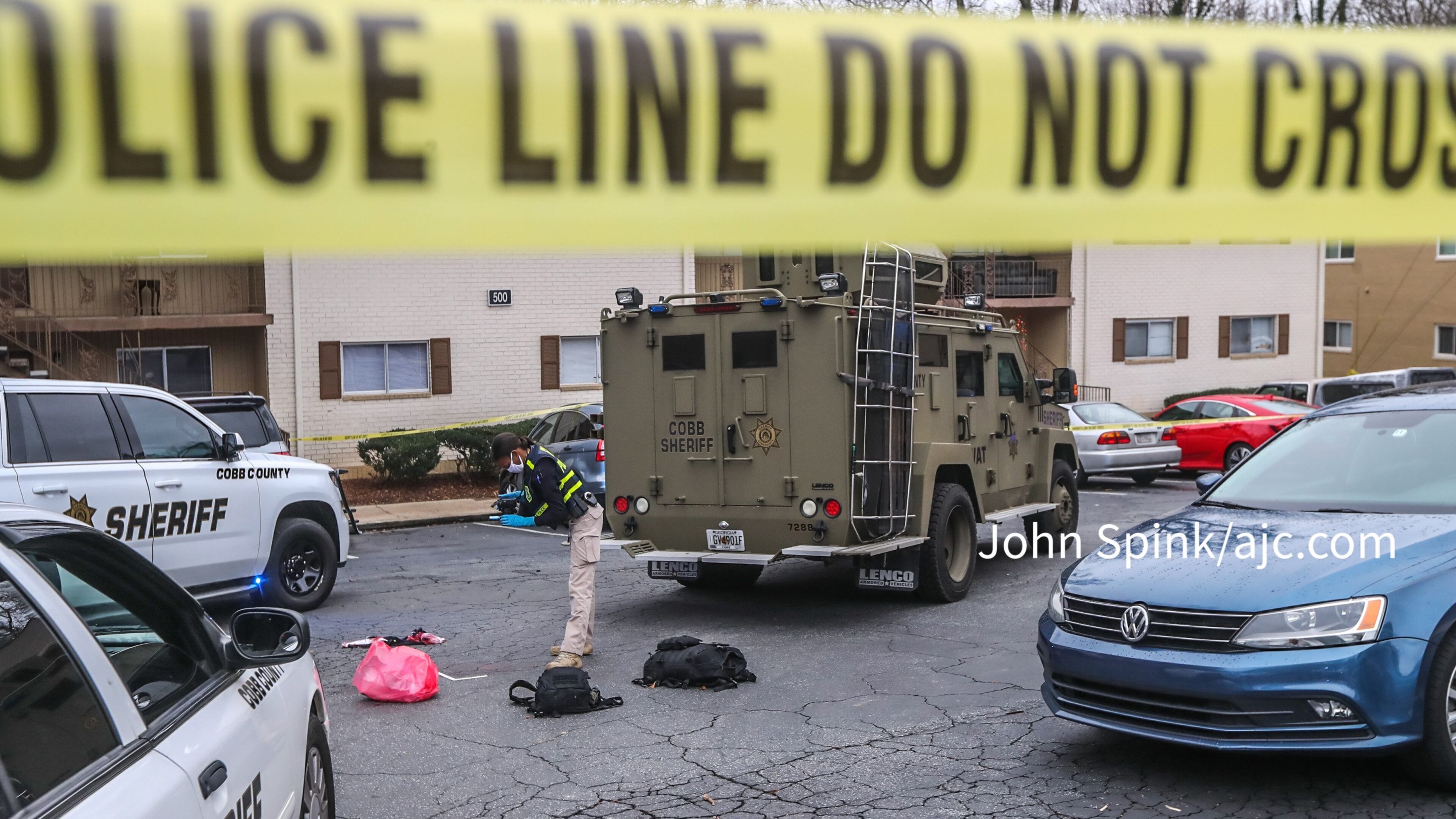 A GBI agent photographs evidence in the parking lot of the Concord Chase Apartments after a shooting.