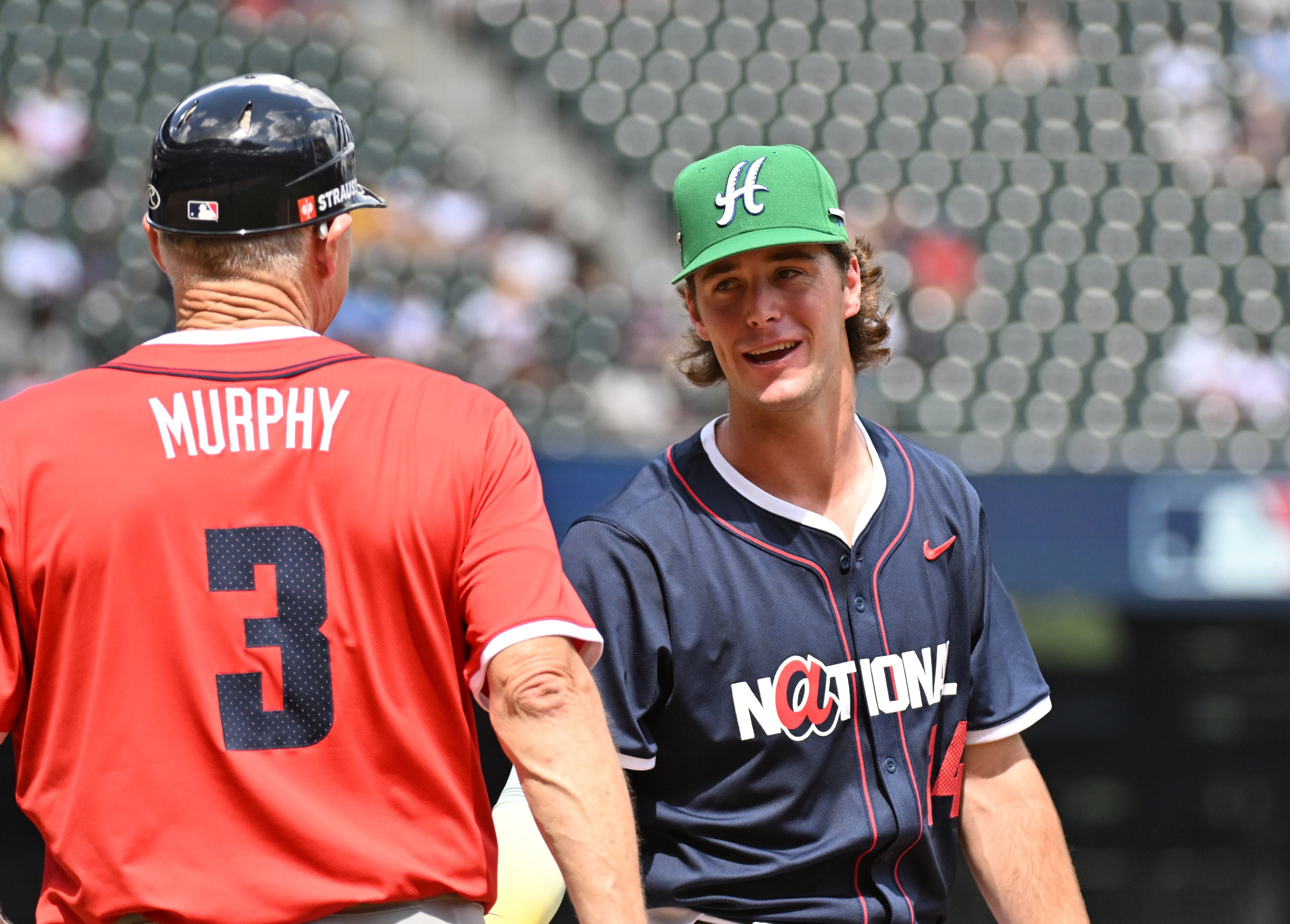 National League infielder Charlie Condon (24) of the Colorado Rockies is greeted by American League first base coach Dale Murphy during the All-Star Futures Game at Truist Park, Saturday, July 12, 2025, in Atlanta. National League won 4-2 over American League. (Hyosub Shin / AJC)