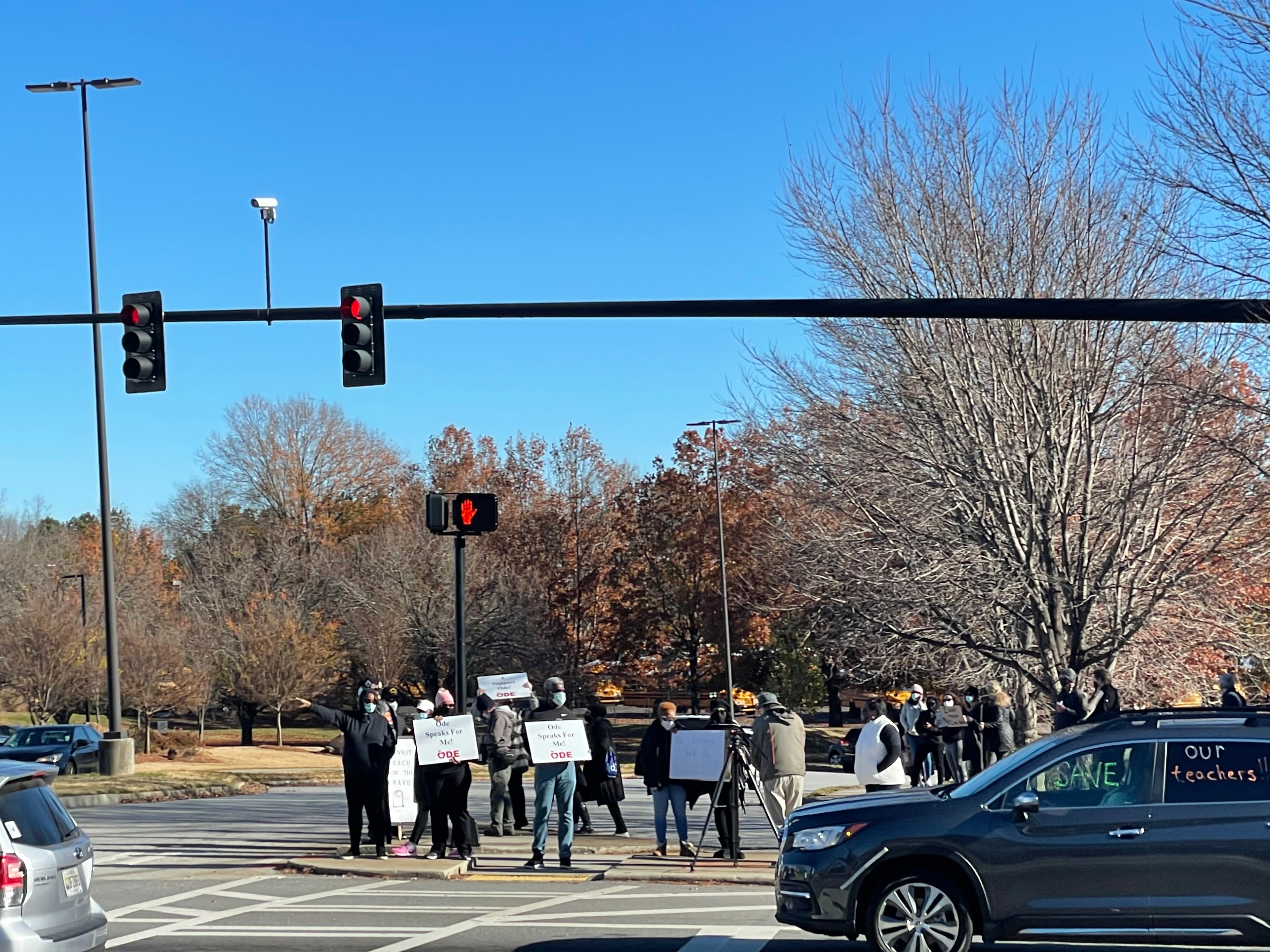 Community members in DeKalb held signs on Tuesday to protest against the reopening of DeKalb County schools.