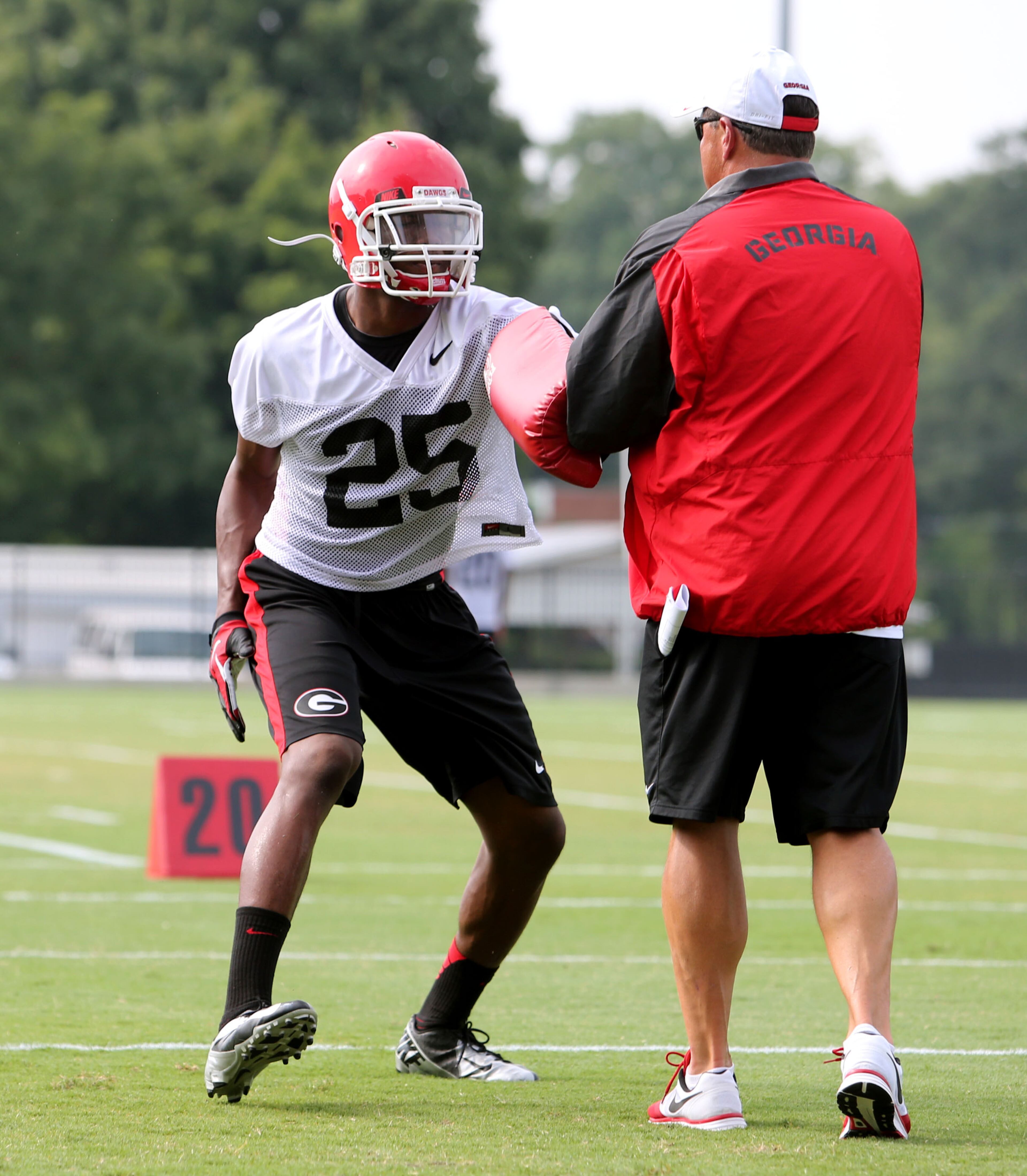 University of Georgia strong safety Josh Harvey-Clemsons (25) participates in a drill with defensive coordinator Todd Grantham during preseason practice at the University of Georgia Tuesday afternoon in Athens, Ga., August 6, 2013. Harvey-Clemsons is a sophomore from Lowndes High School in Valdosta, Ga.. Harvey-Clemons, who is slated to start at strong safety, is suspended for the Aug. 31 game at Clemson. JASON GETZ / JGETZ@AJC.COM